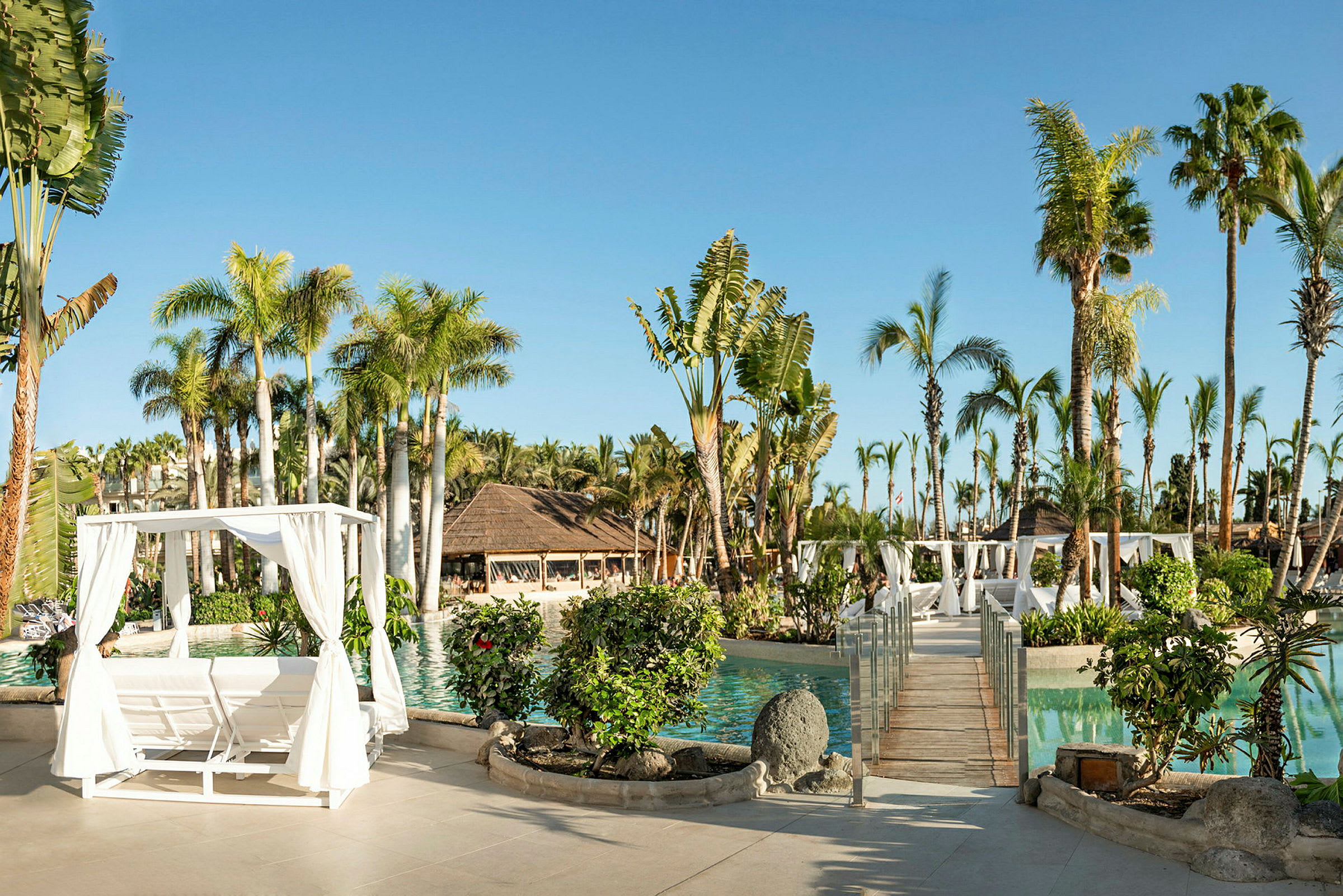 Solig resort med pool, palmer, träpergola och planteringar. (AI-genererad text)