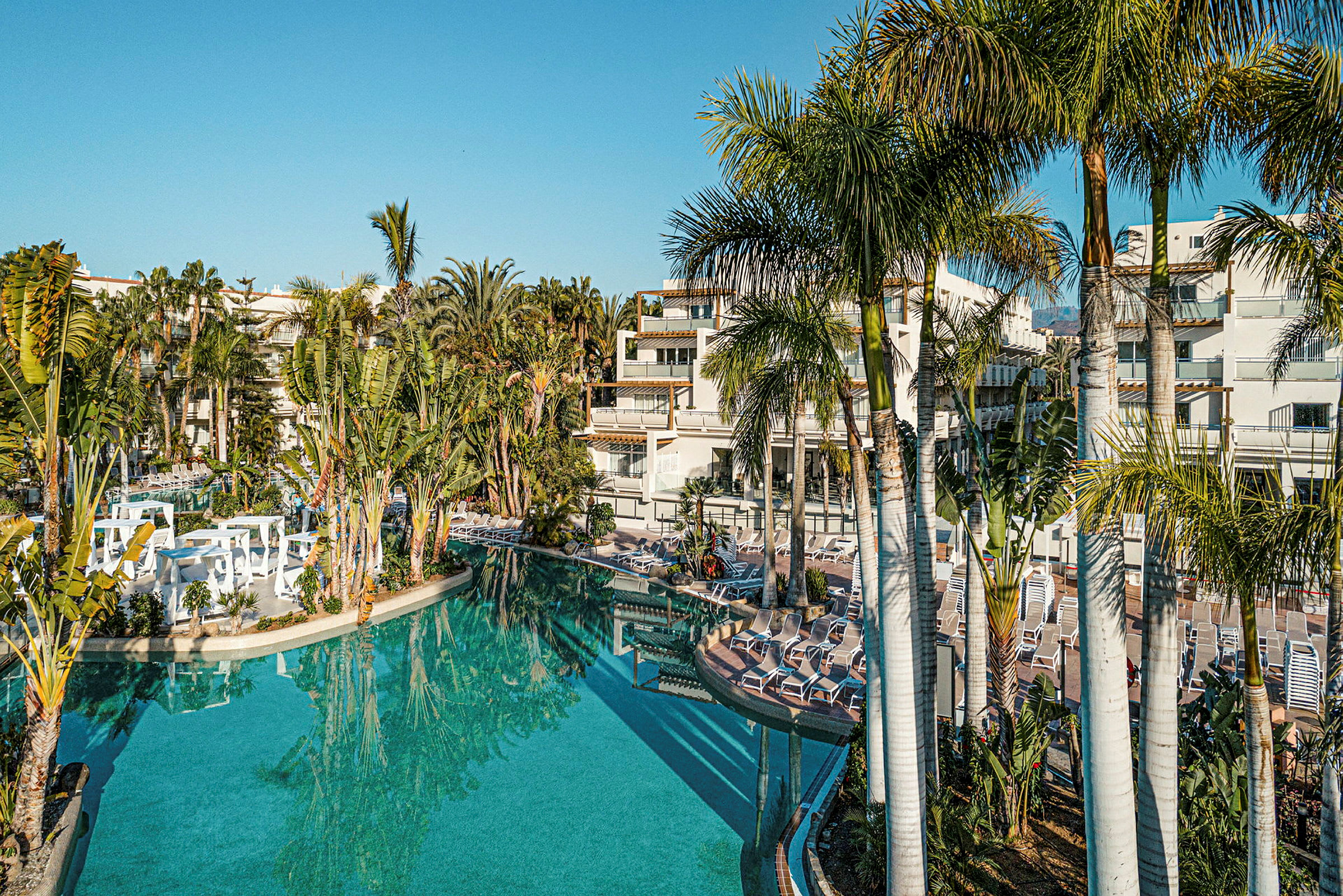 Hotellbyggnad med pool och omgivande palmer. (AI-genererad text)