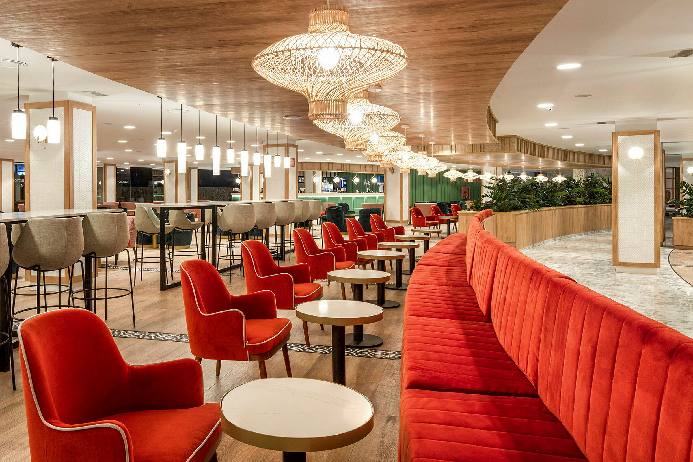 En restaurang med röda fåtöljer och bänkar, ljusa bord och moderna taklampor. (AI-genererad text)