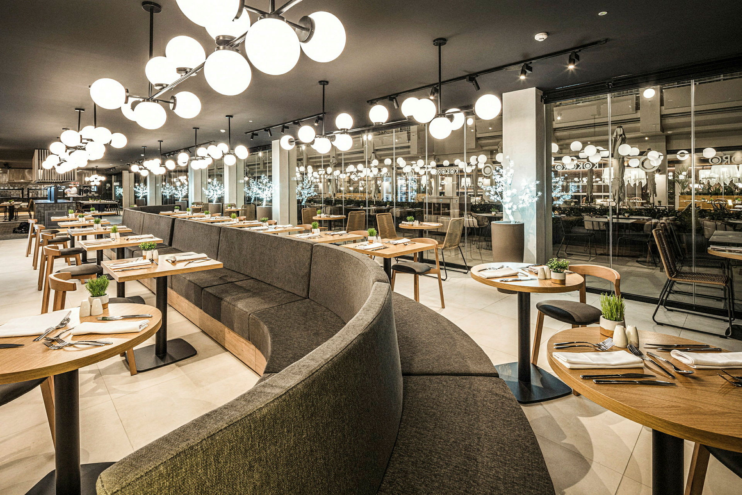 Modern restaurangmiljö med bågformade sittplatser och runda bord, elegant inrett. (AI-genererad text)