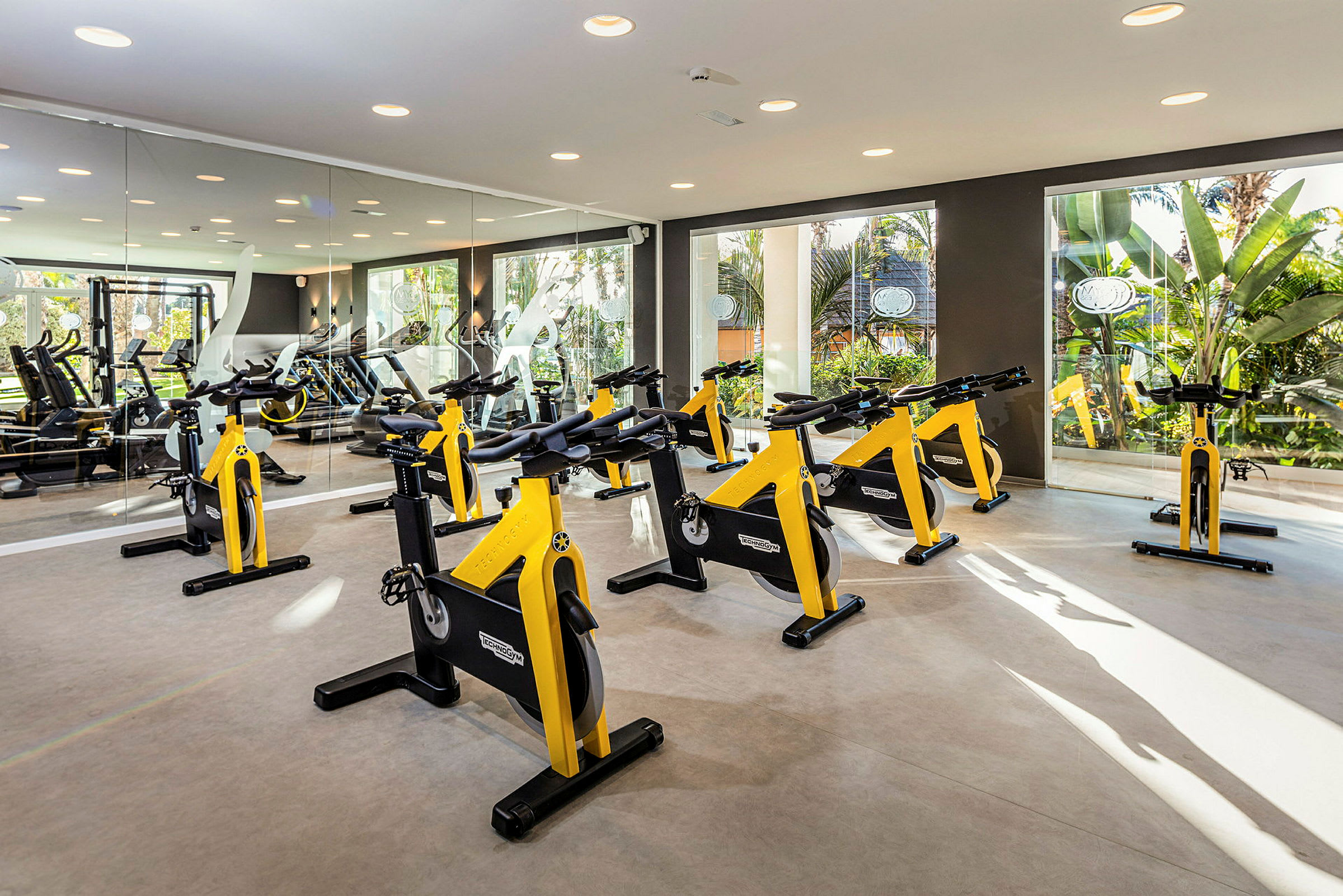 Ett gym med flera gula träningscyklar placerade i ett väl upplyst rum. (AI-genererad text)