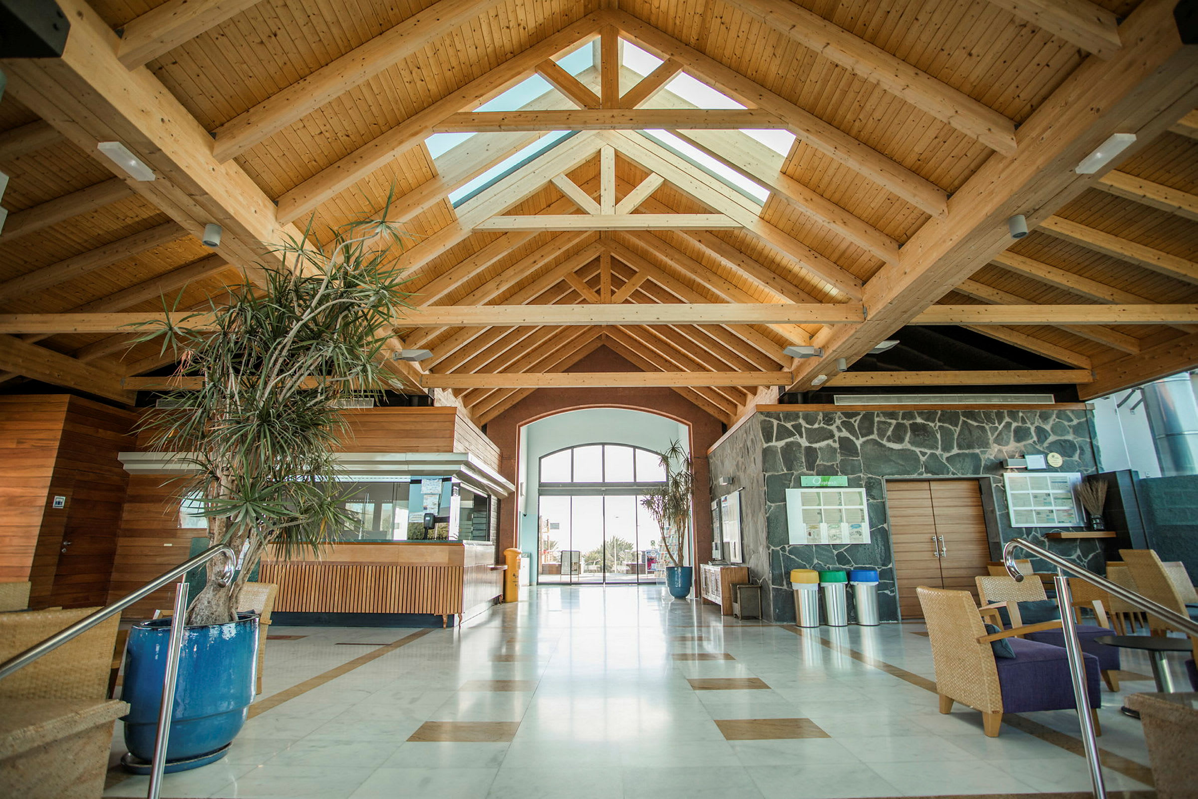 Lobby med högt tak av träbjälkar, panoramafönster och modern inredning. (AI-genererad text)