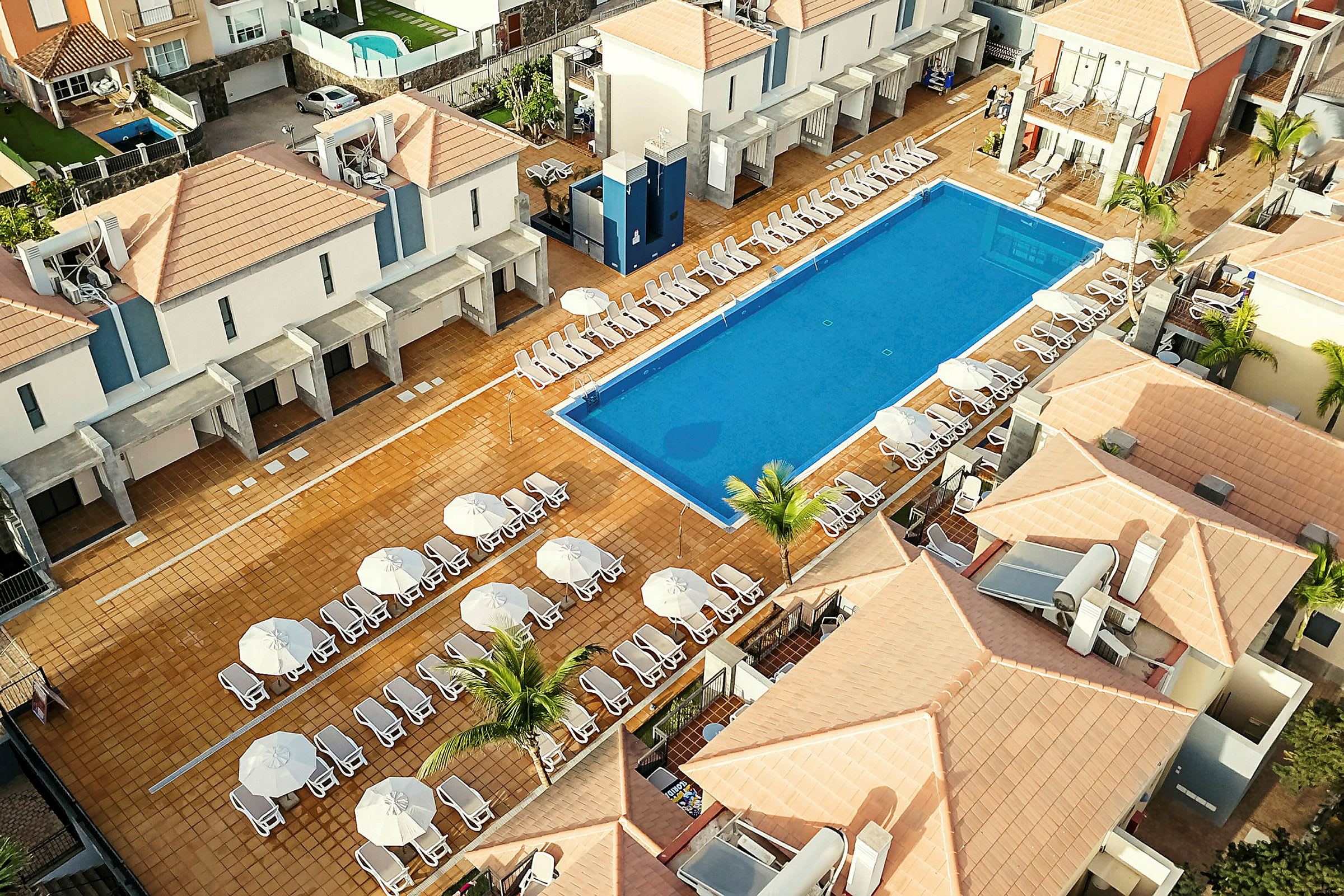 Ett hotellområde med pool och solstolar. (AI-genererad text)