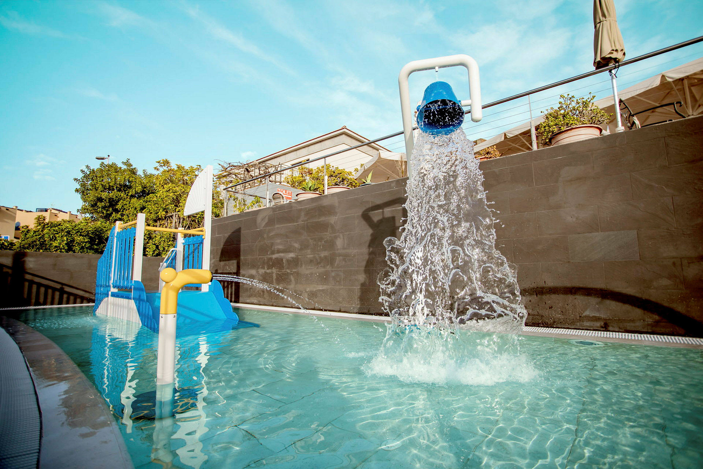 Lekplats med vattenstråle och liten rutschkana i pool. (AI-genererad text)