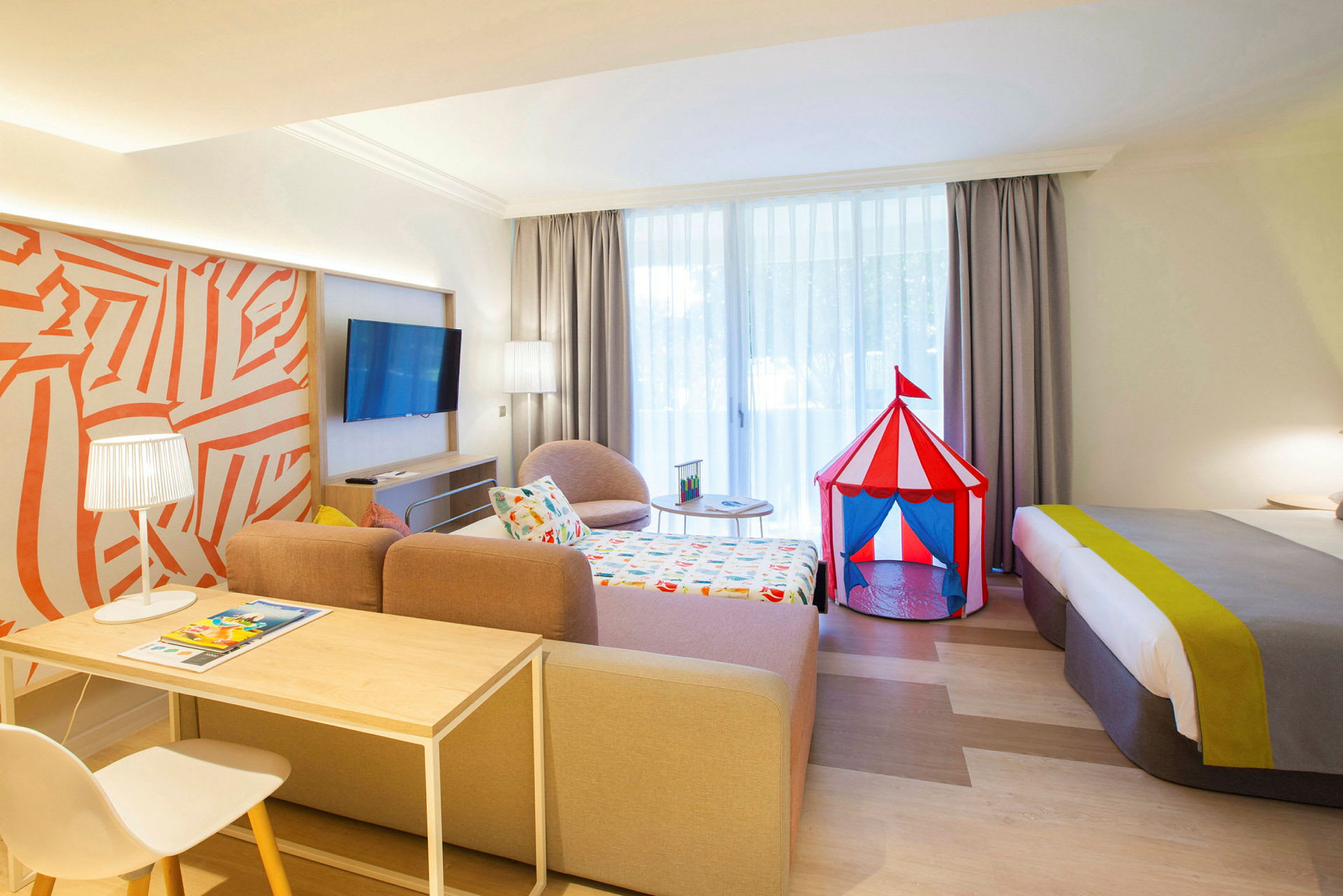 Ett hotellrum med en färgglad cirkustältleksak bredvid sängen. (AI-genererad text)