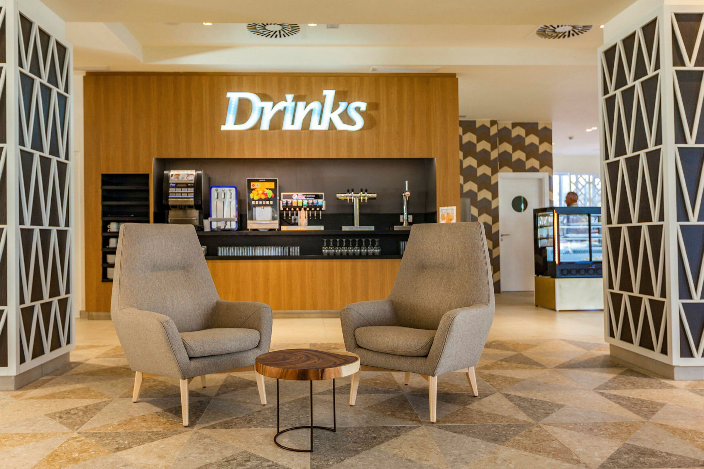 Två fåtöljer och ett litet bord framför en dryckesstation. (AI-genererad text)
