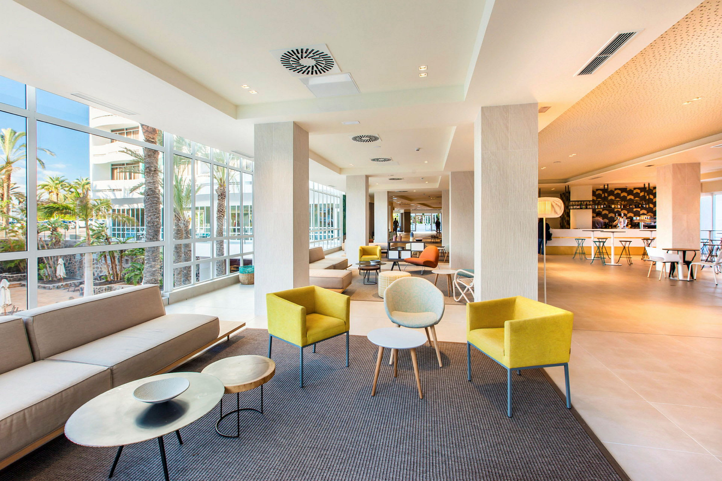En ljus hotellobby med olika sittgrupper och stora fönster. (AI-genererad text)