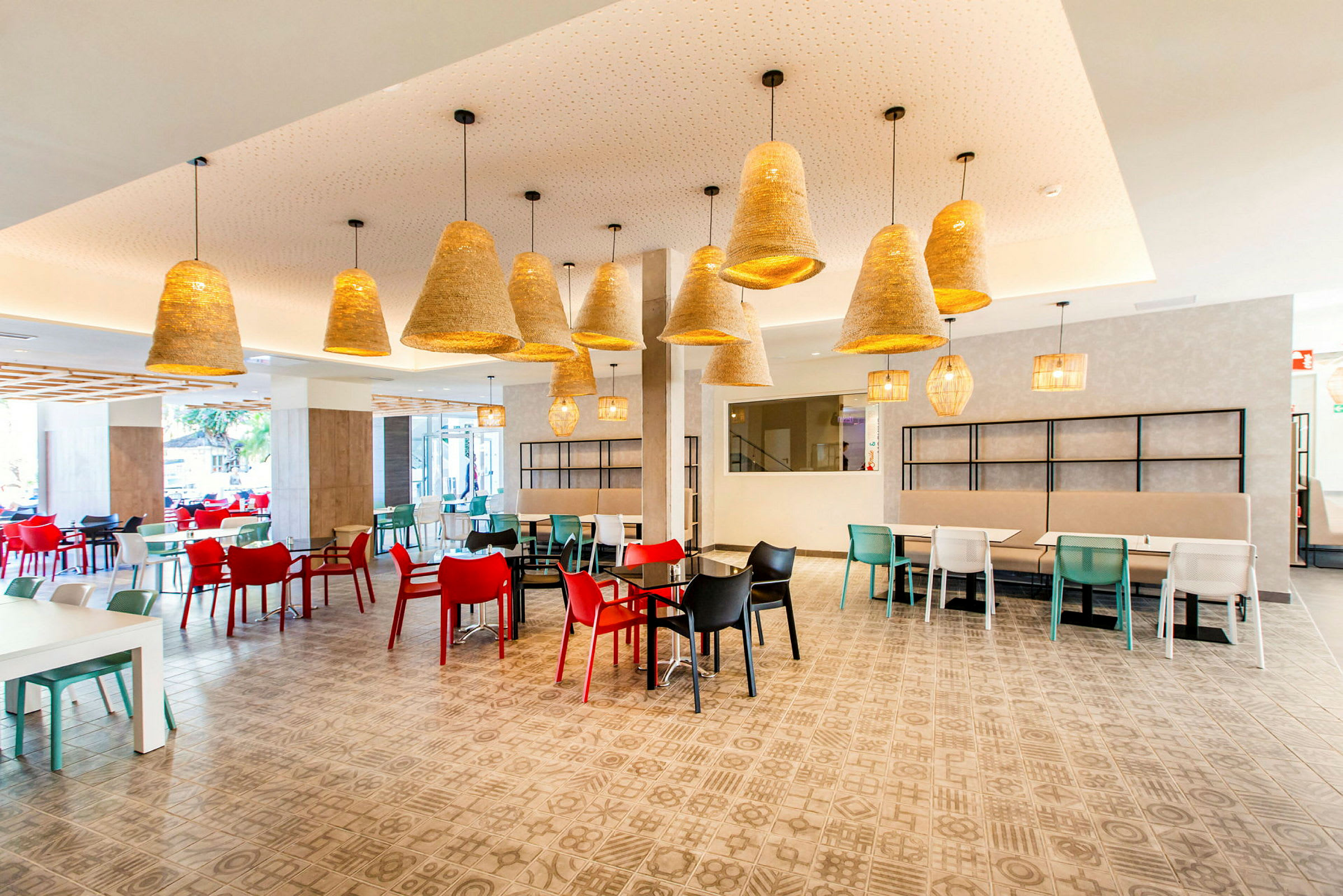 Interiör av en restaurang med färgglada stolar och hängande lampor. (AI-genererad text)