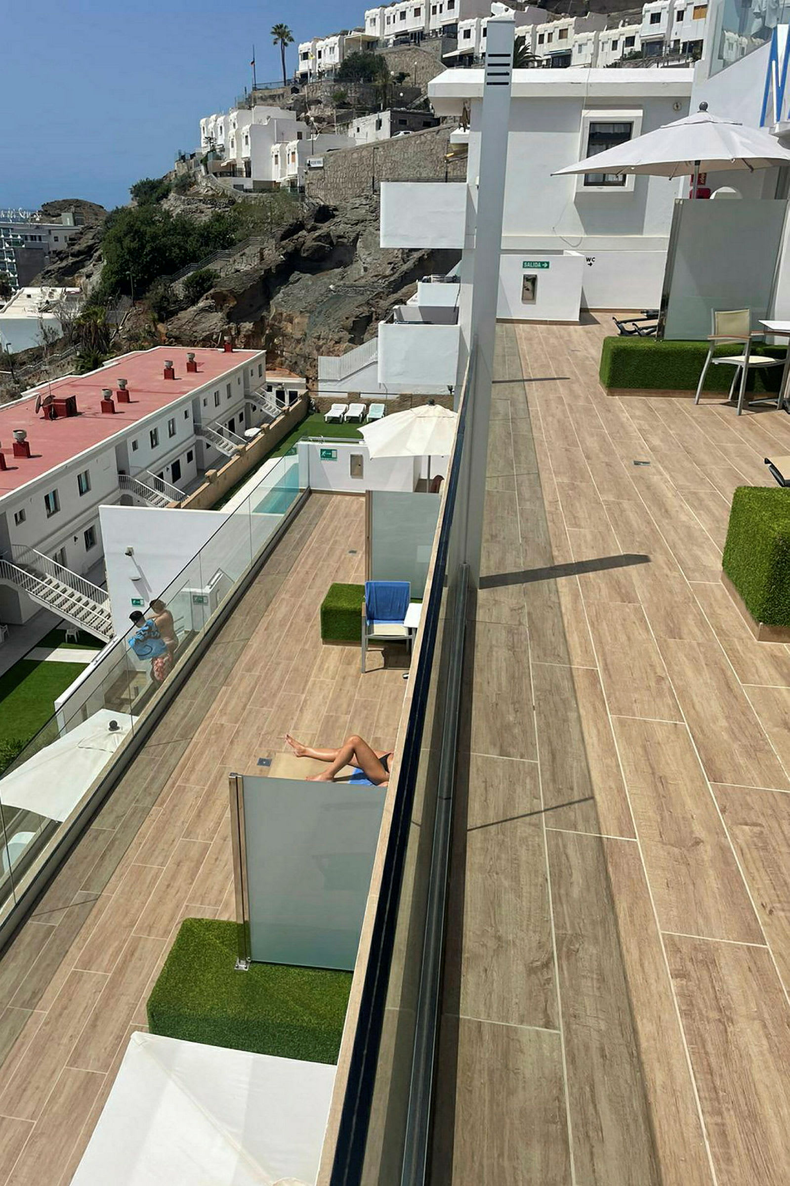 En solterrass med utsikt över ett hotellområde på en bergssluttning. (AI-genererad text)