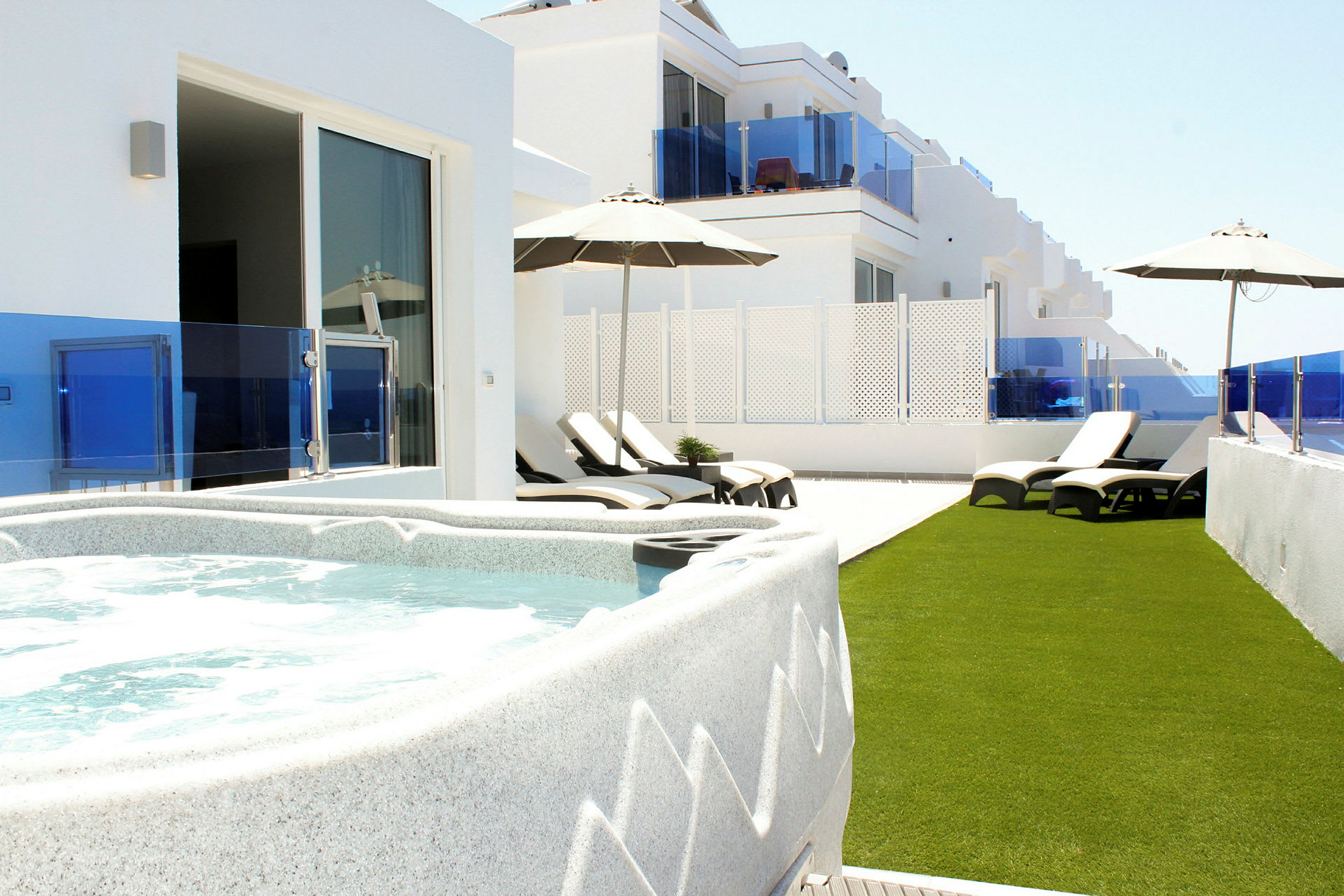 Terrass med jacuzzi, solstolar och parasoller. (AI-genererad text)
