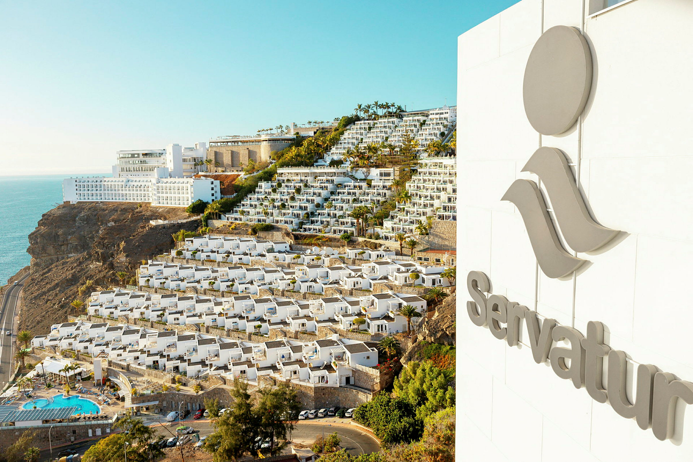 Vy över ett hotell på en sluttning med havet i bakgrunden. (AI-genererad text)