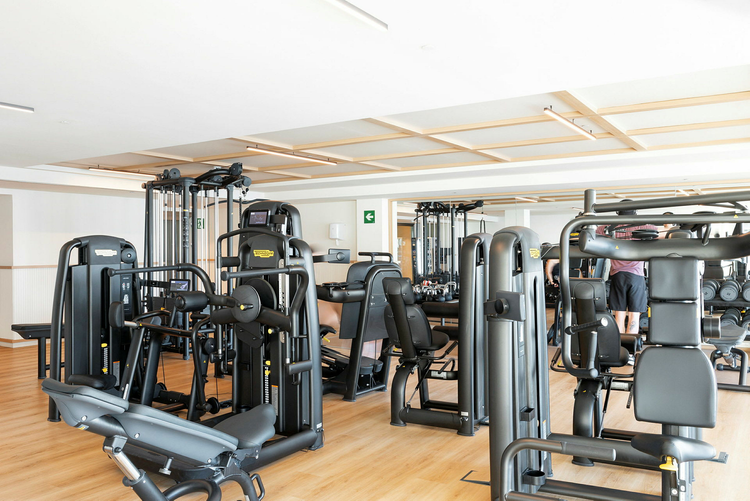 Bild av ett gym med träningsmaskiner och några personer. (AI-genererad text)