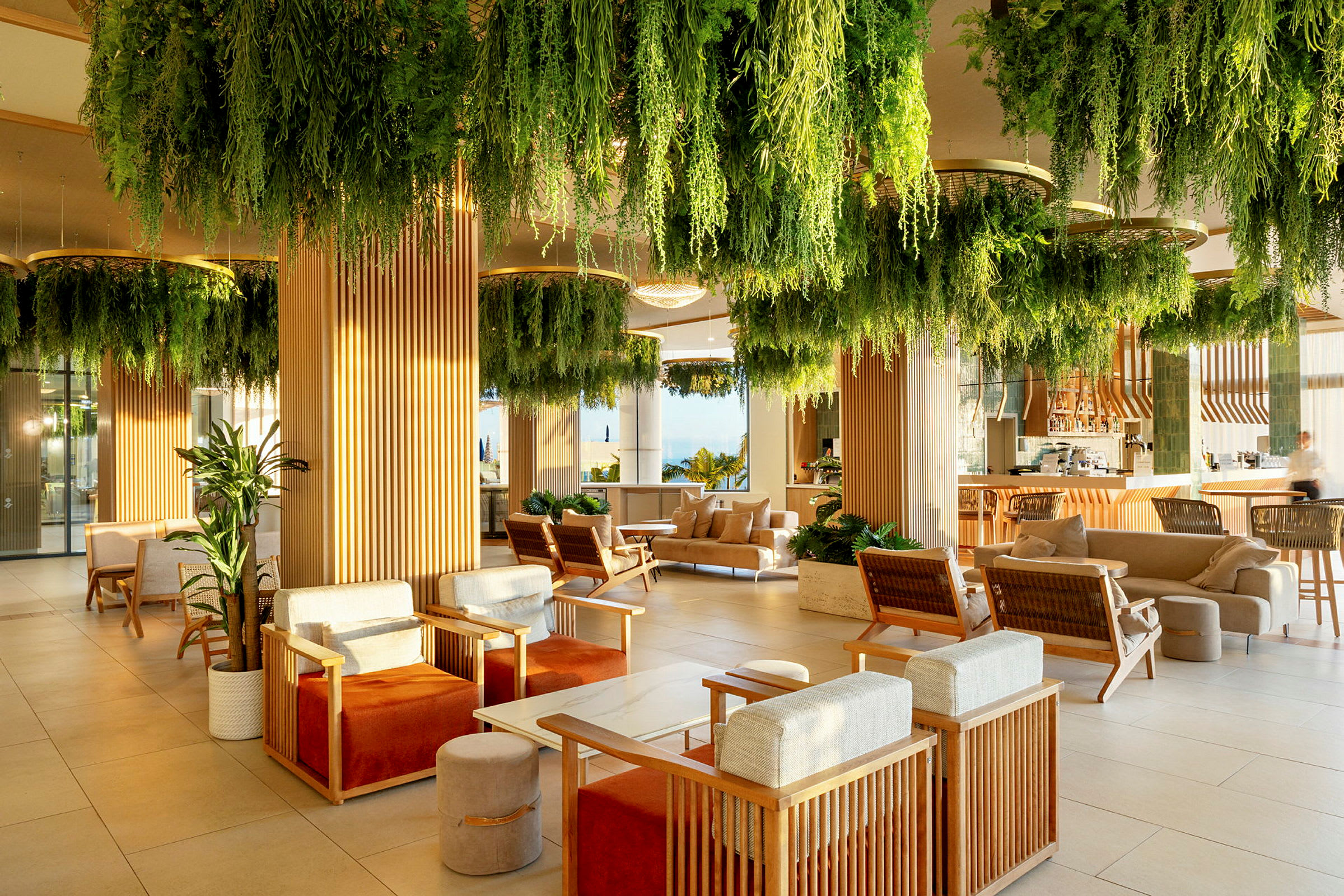 En modern lounge med sittgrupper och gröna växter som hänger från taket. (AI-genererad text)