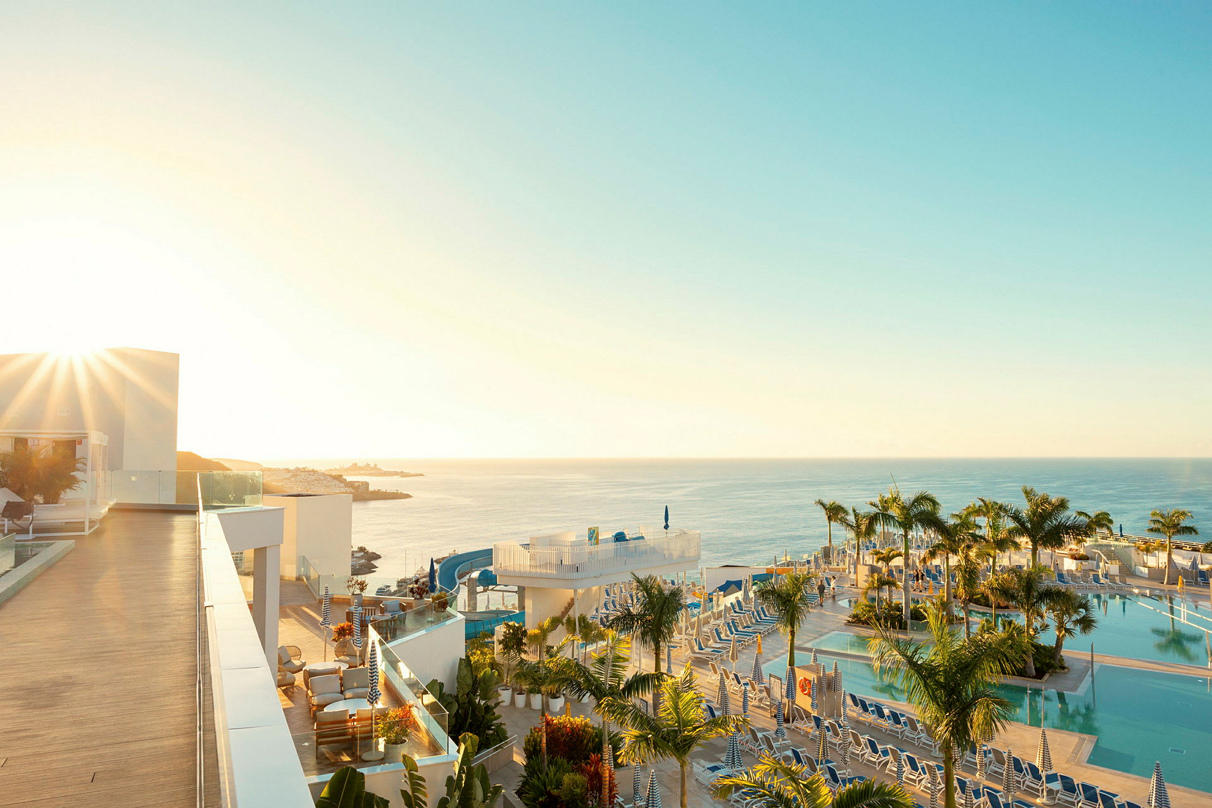 Soluppgång över en resort med poolområde och utsikt över havet. (AI-genererad text)