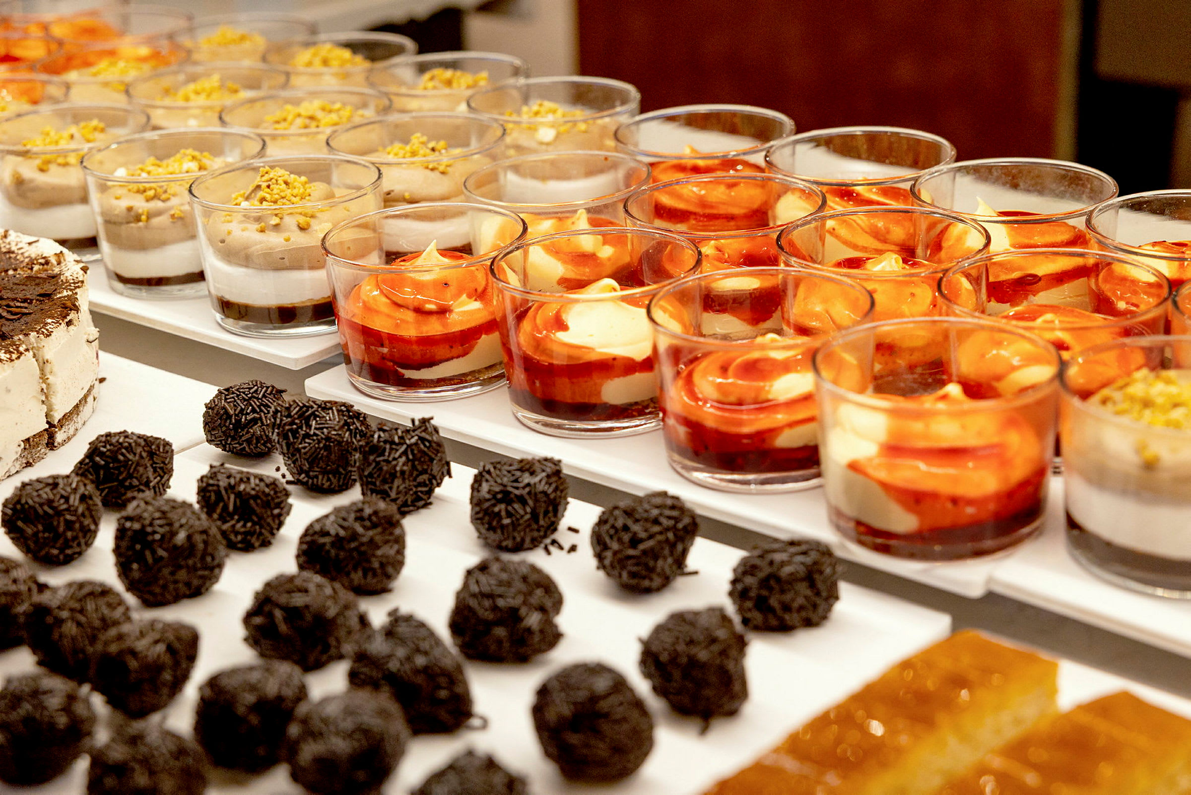 En buffé med olika desserter, inklusive chokladbollar, glasstårta och desserter i glas. (AI-genererad text)