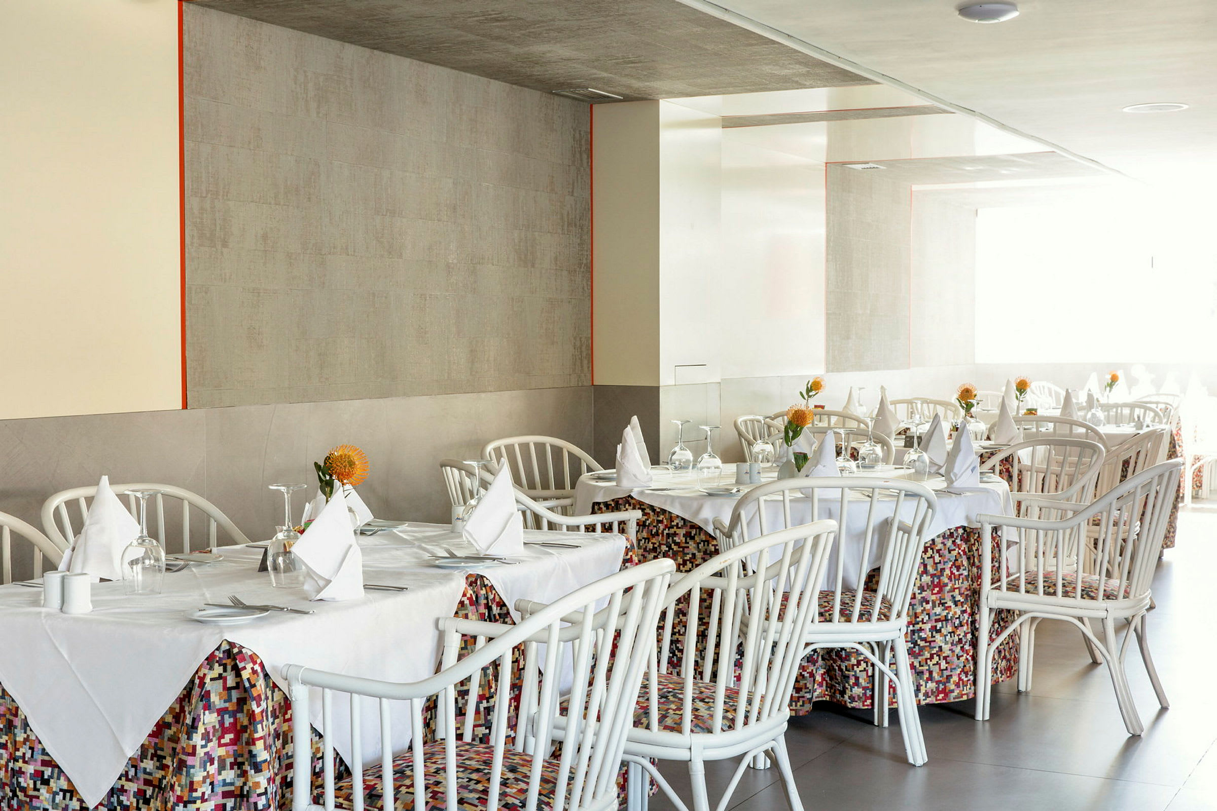 En inomhusrestaurang med dukade bord och vita stolar. (AI-genererad text)