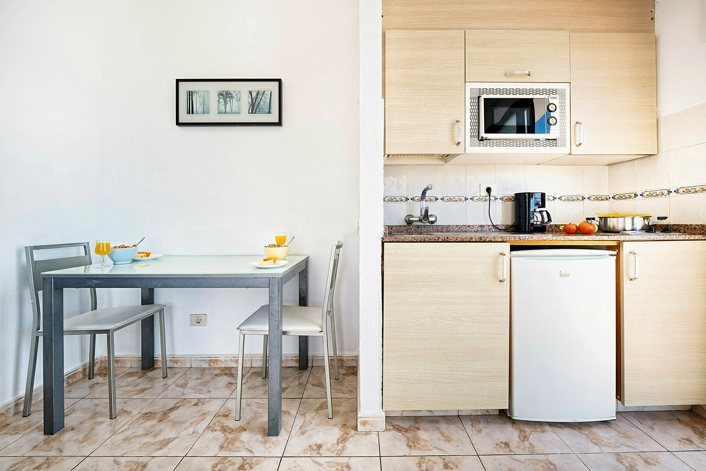 Ett litet kök med en matplats och moderna apparater. (AI-genererad text)