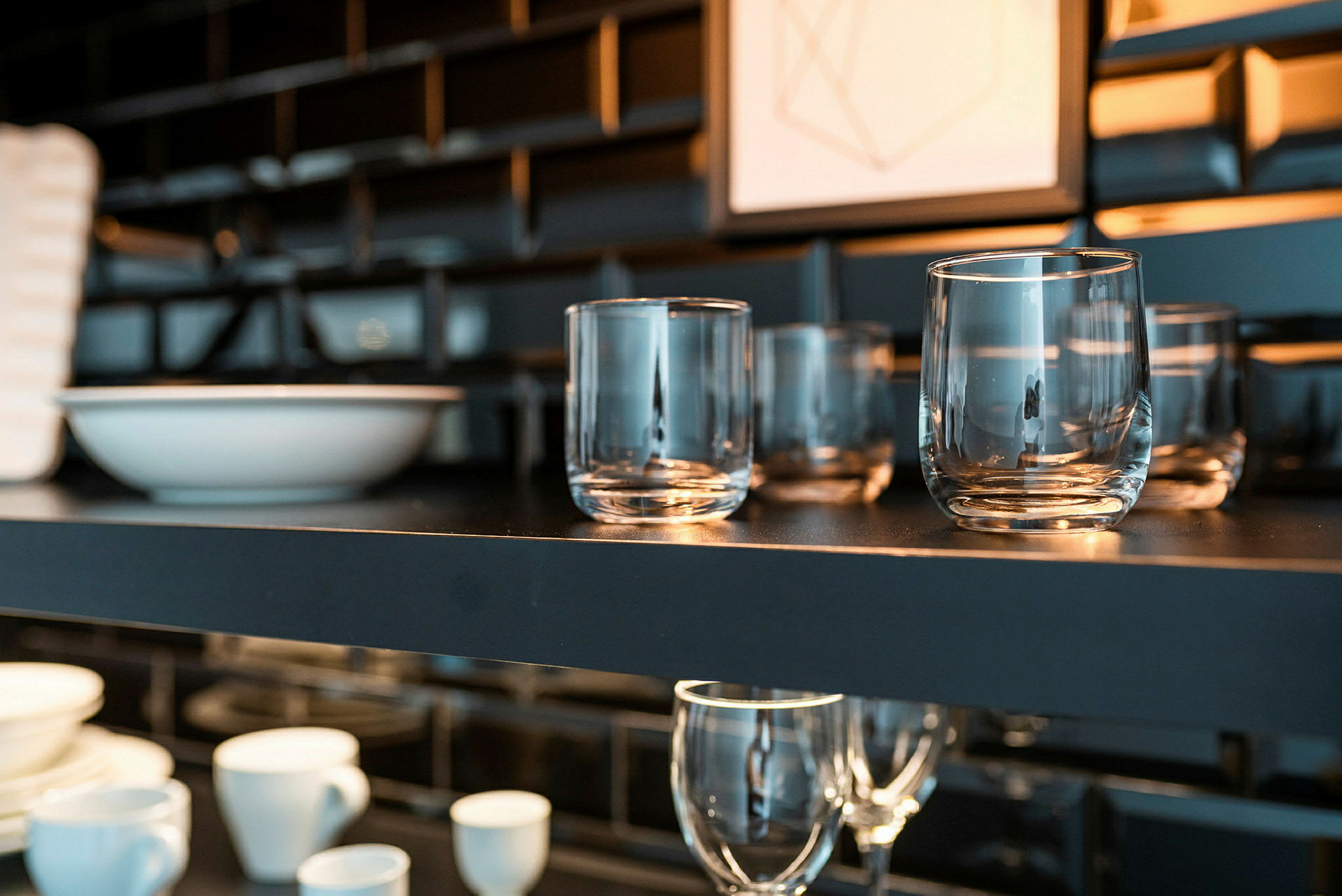 Hylla med glas och skålar i ett mörkt kök. (AI-genererad text)