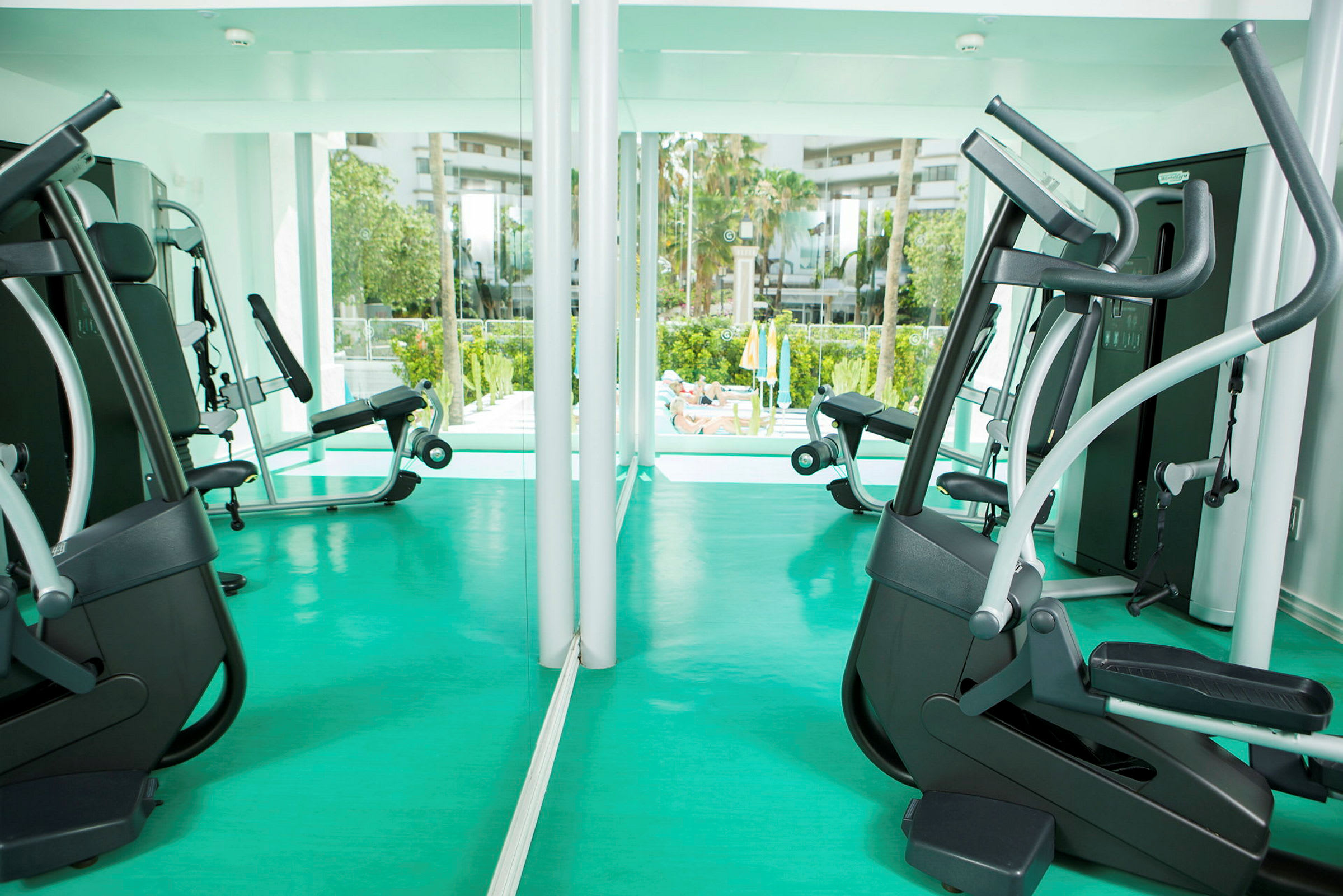 Gym med träningsutrustning och utsikt mot ett utomhusområde. (AI-genererad text)