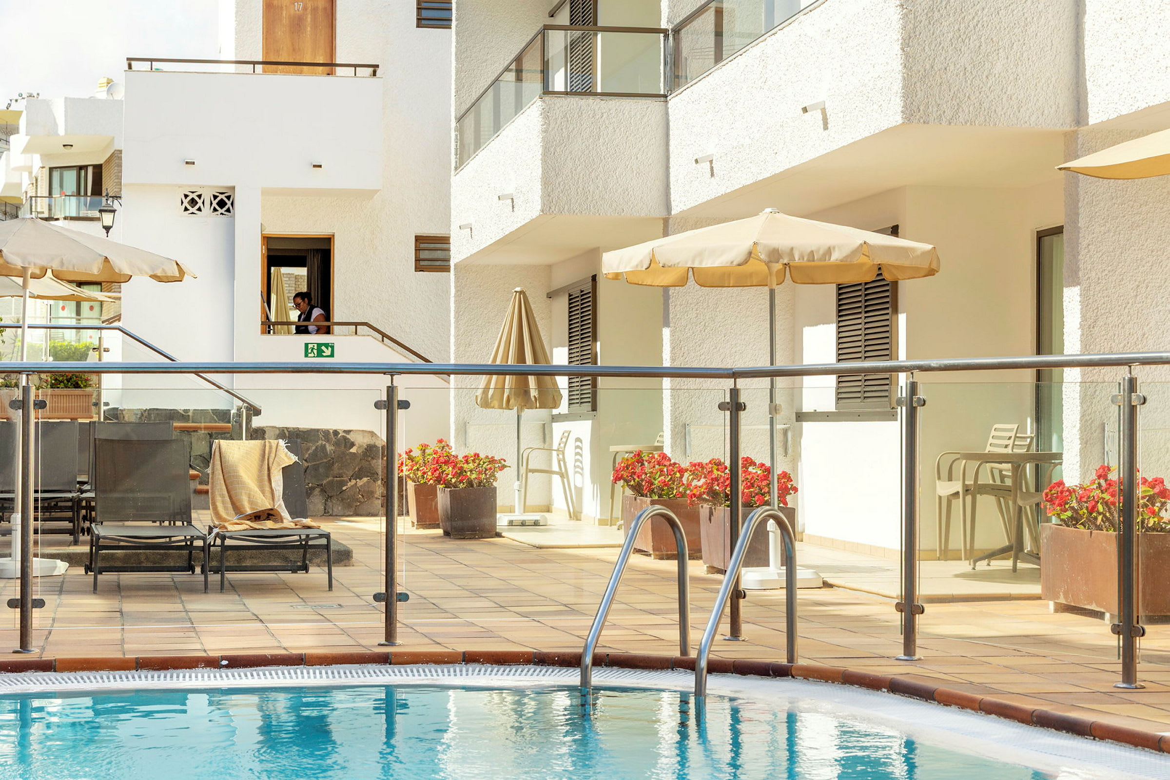 En pool framför en solterrass med stolar och parasoll. (AI-genererad text)