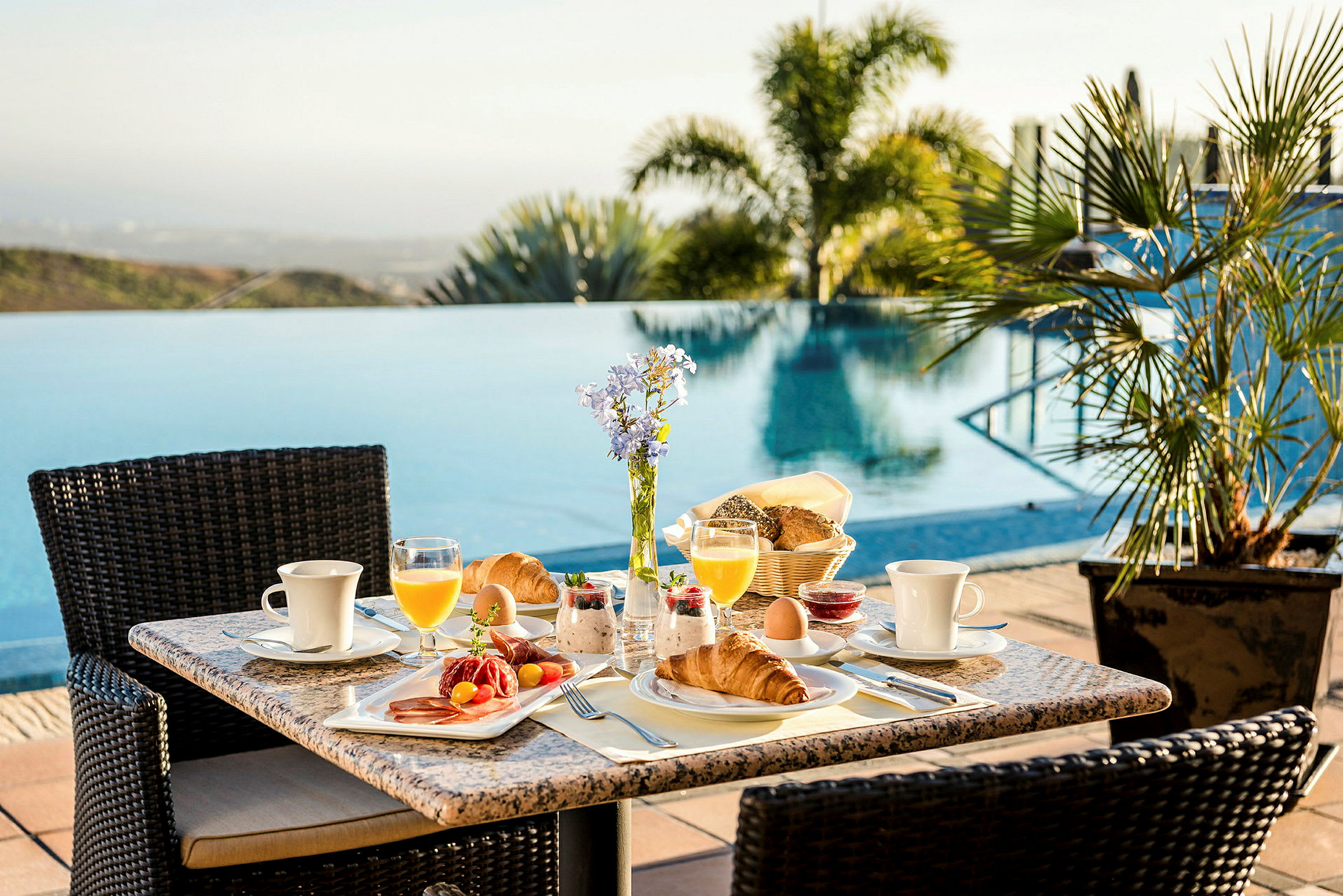 Frukost uppdukad på ett bord vid sidan av en pool. (AI-genererad text)