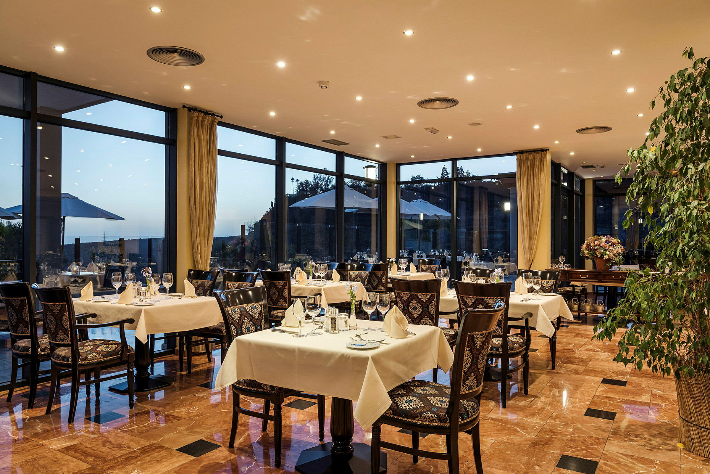 Restaurang med dukade bord och utsikt genom stora fönster. (AI-genererad text)