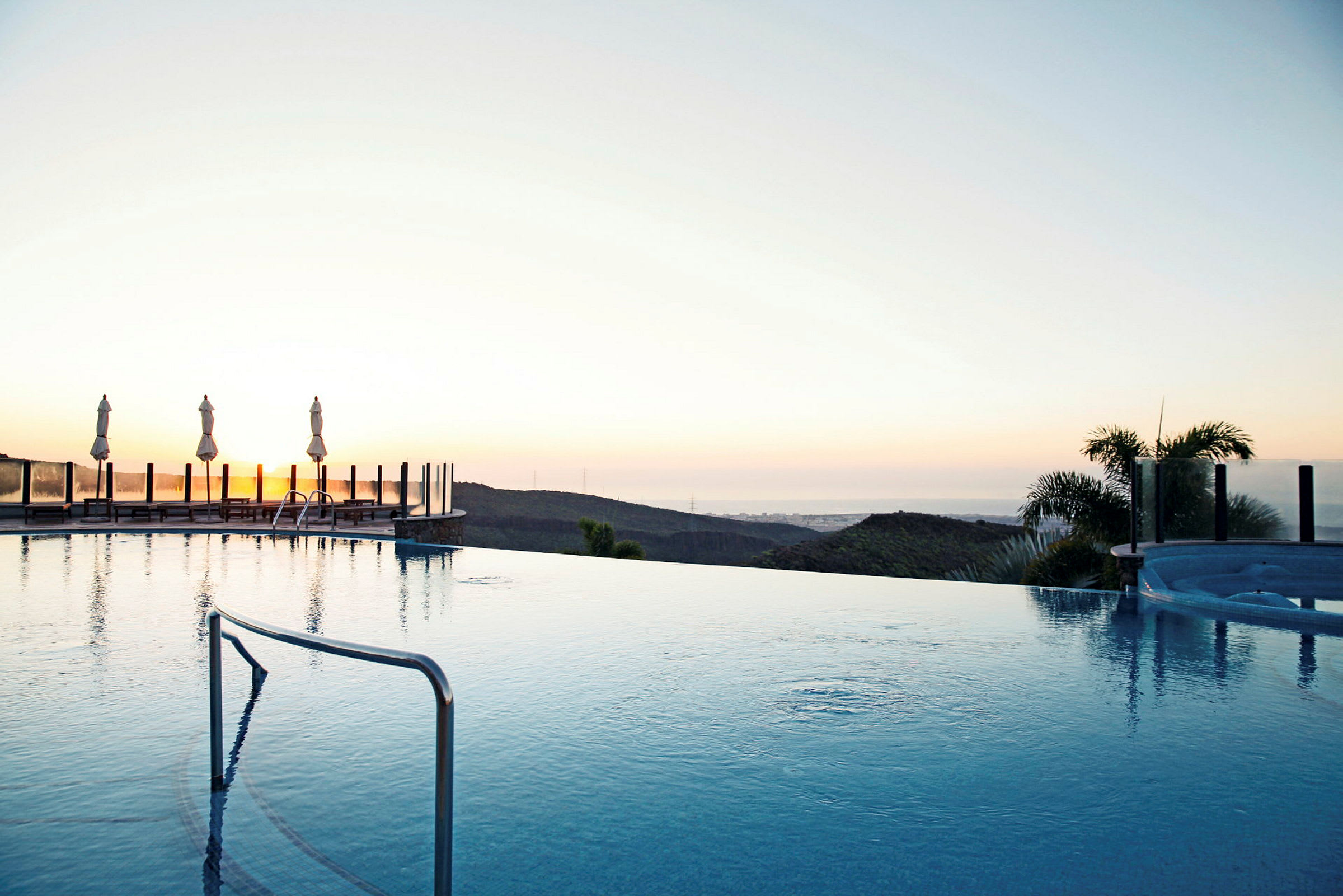 En infinitypool med utsikt över ett landskap vid solnedgången. (AI-genererad text)