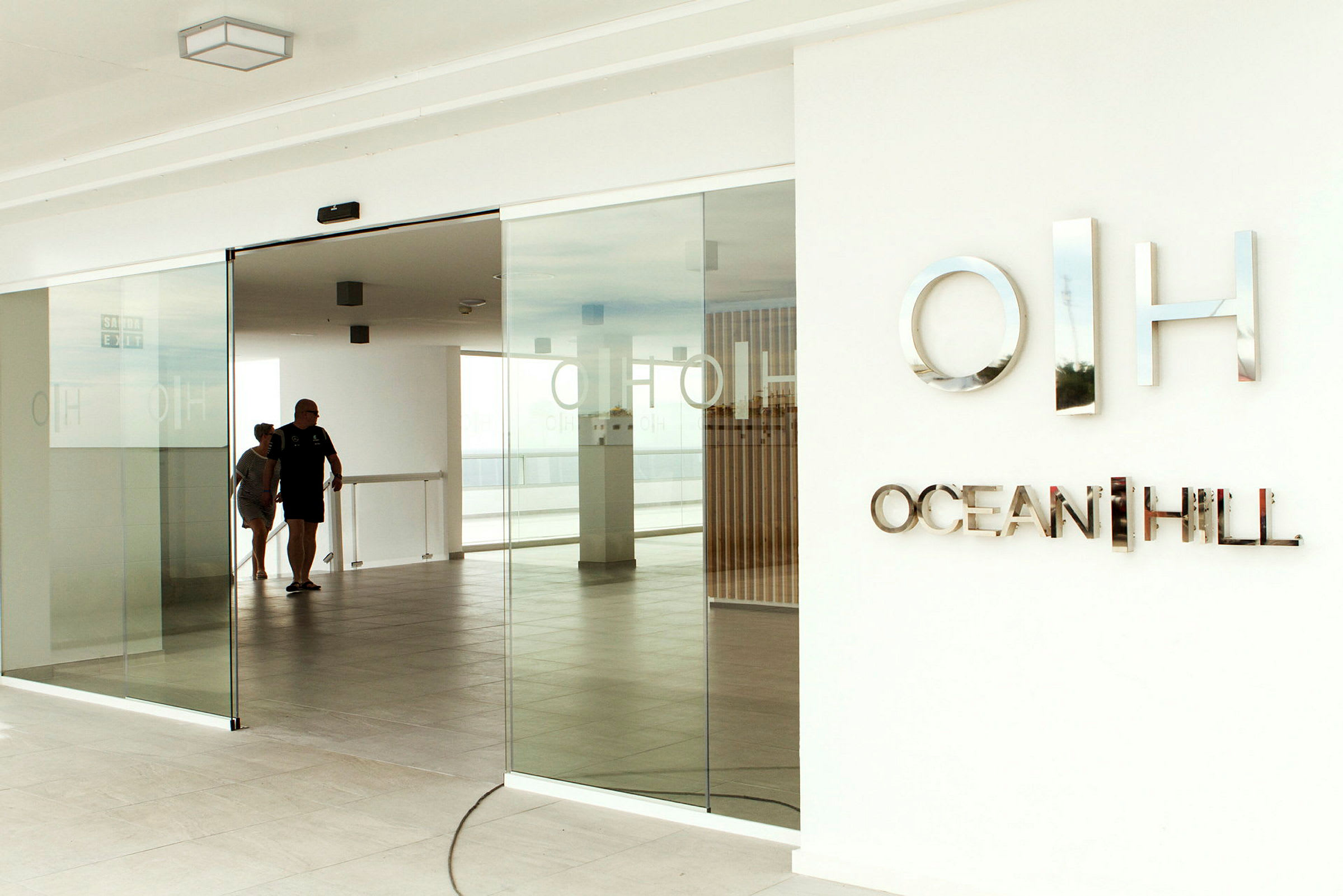Entré med glasdörrar och skylten 'Ocean Hill'. (AI-genererad text)