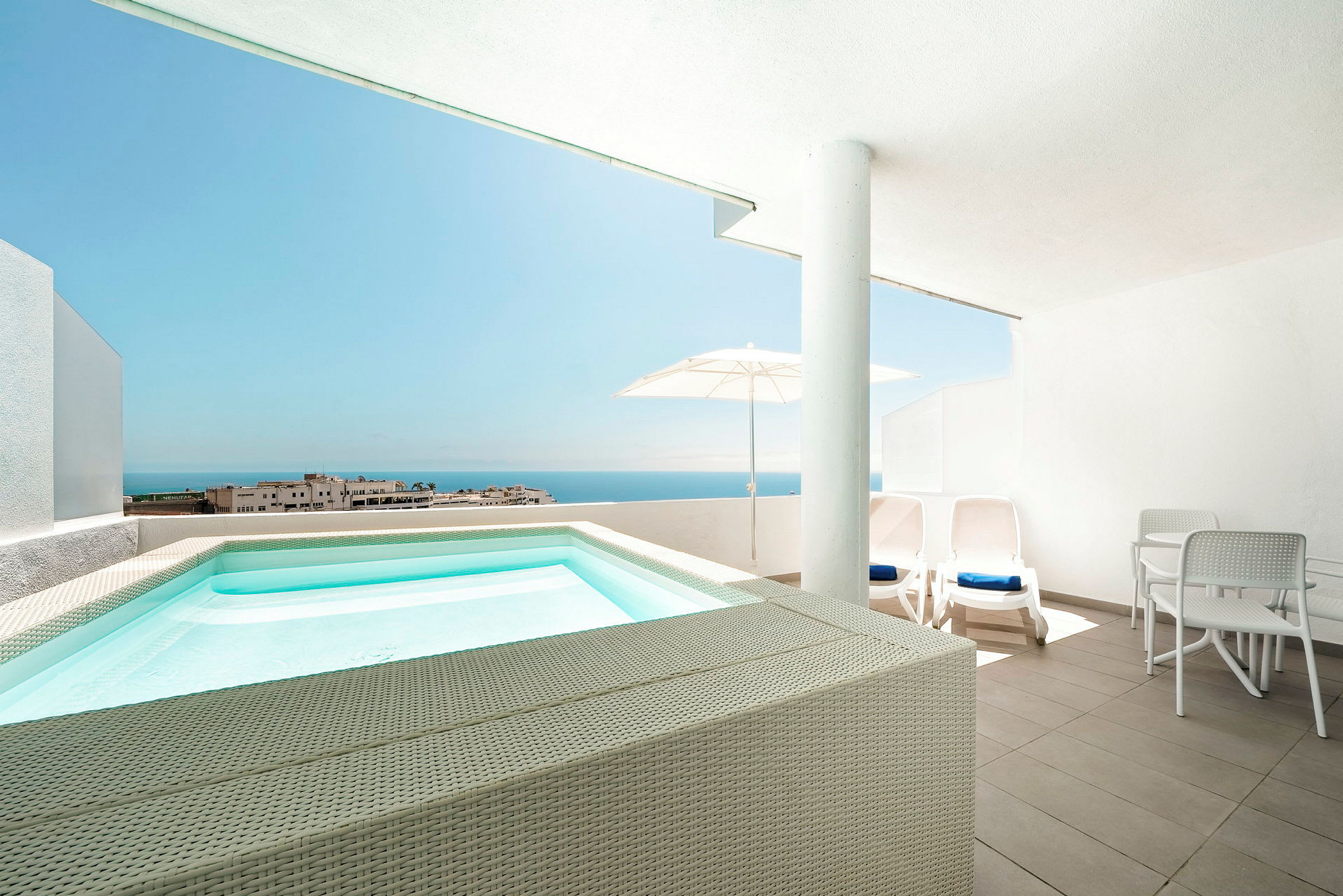 Terrass med liten pool, solstolar och utsikt mot havet. (AI-genererad text)