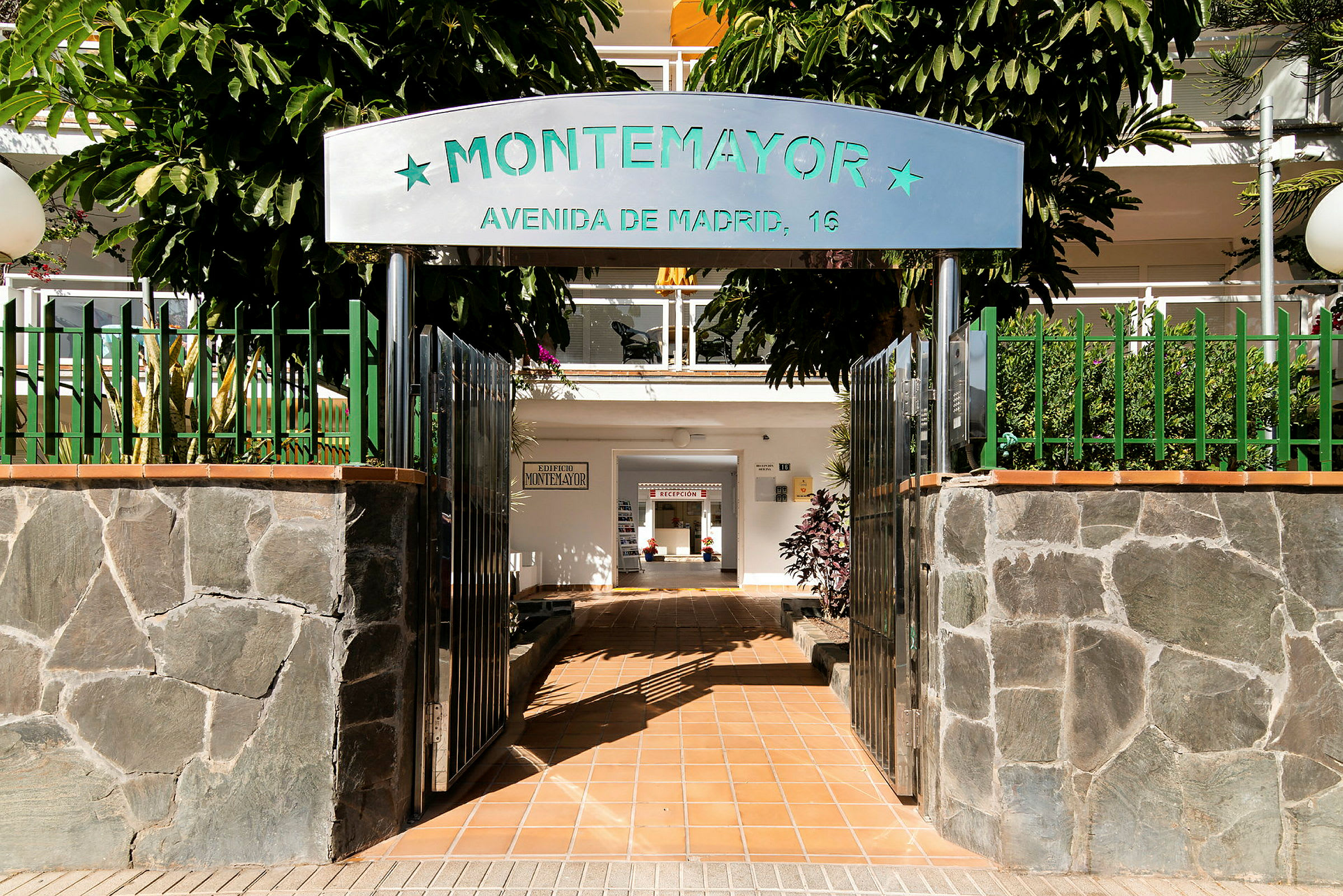 Entré till byggnad med skylten 'Montemayor' och en gångväg inomhus. (AI-genererad text)