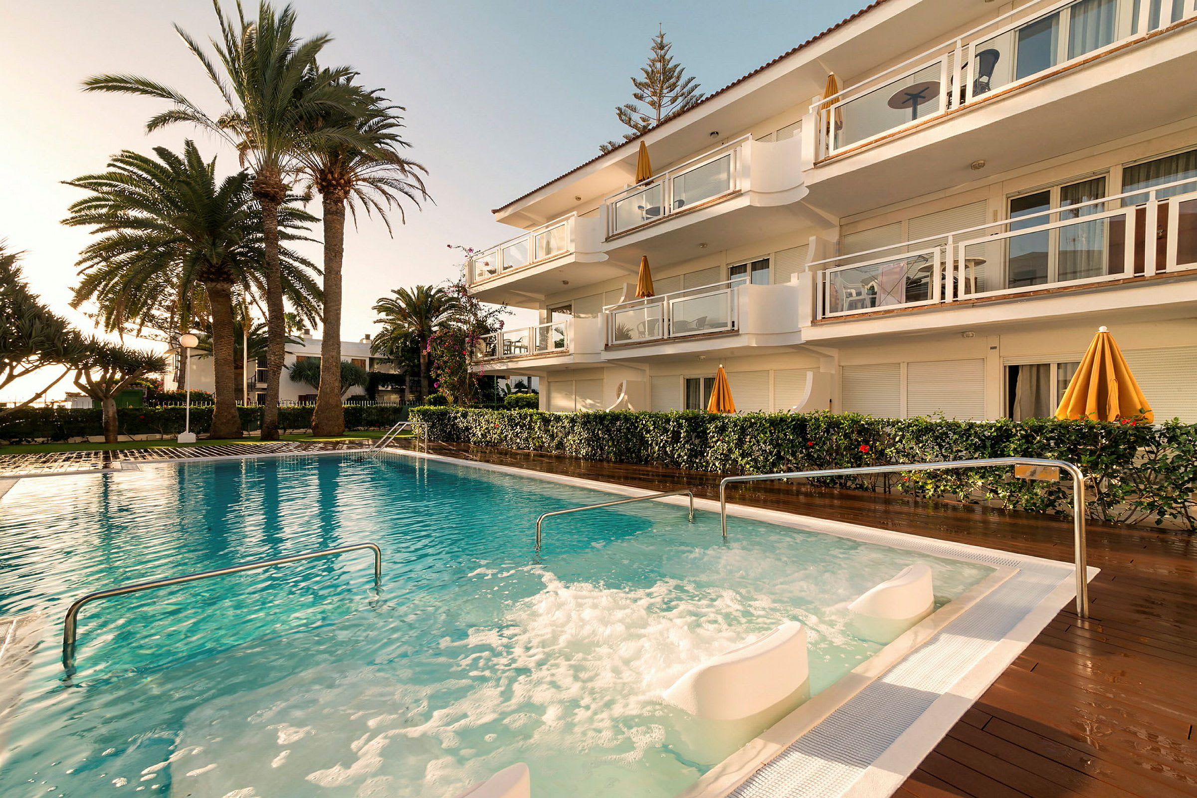 Utomhuspool med bubbelzon vid ett hotell omgivet av palmer. (AI-genererad text)