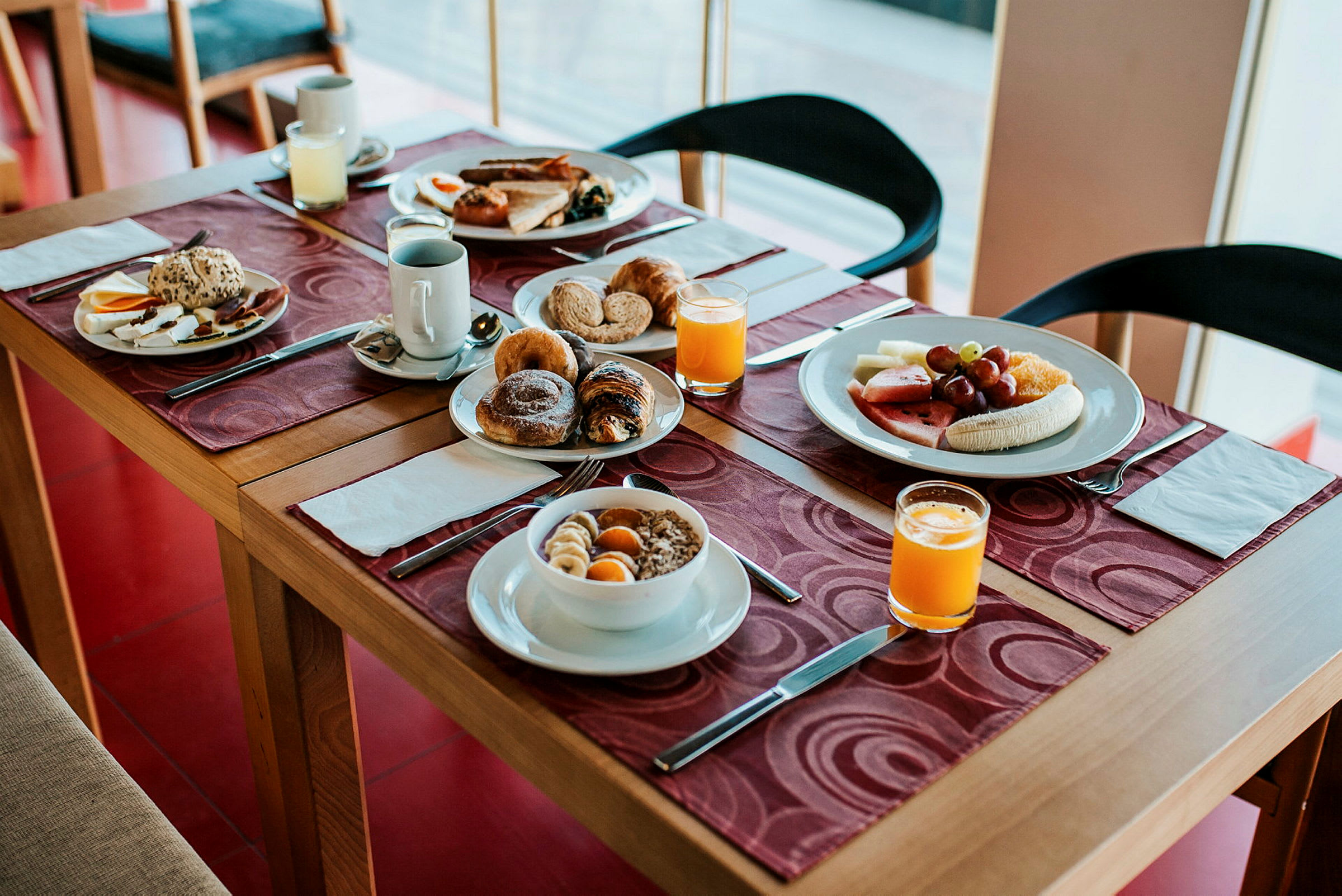 Frukostbord innehållande bröd, frukt, juice och andra måltider. (AI-genererad text)