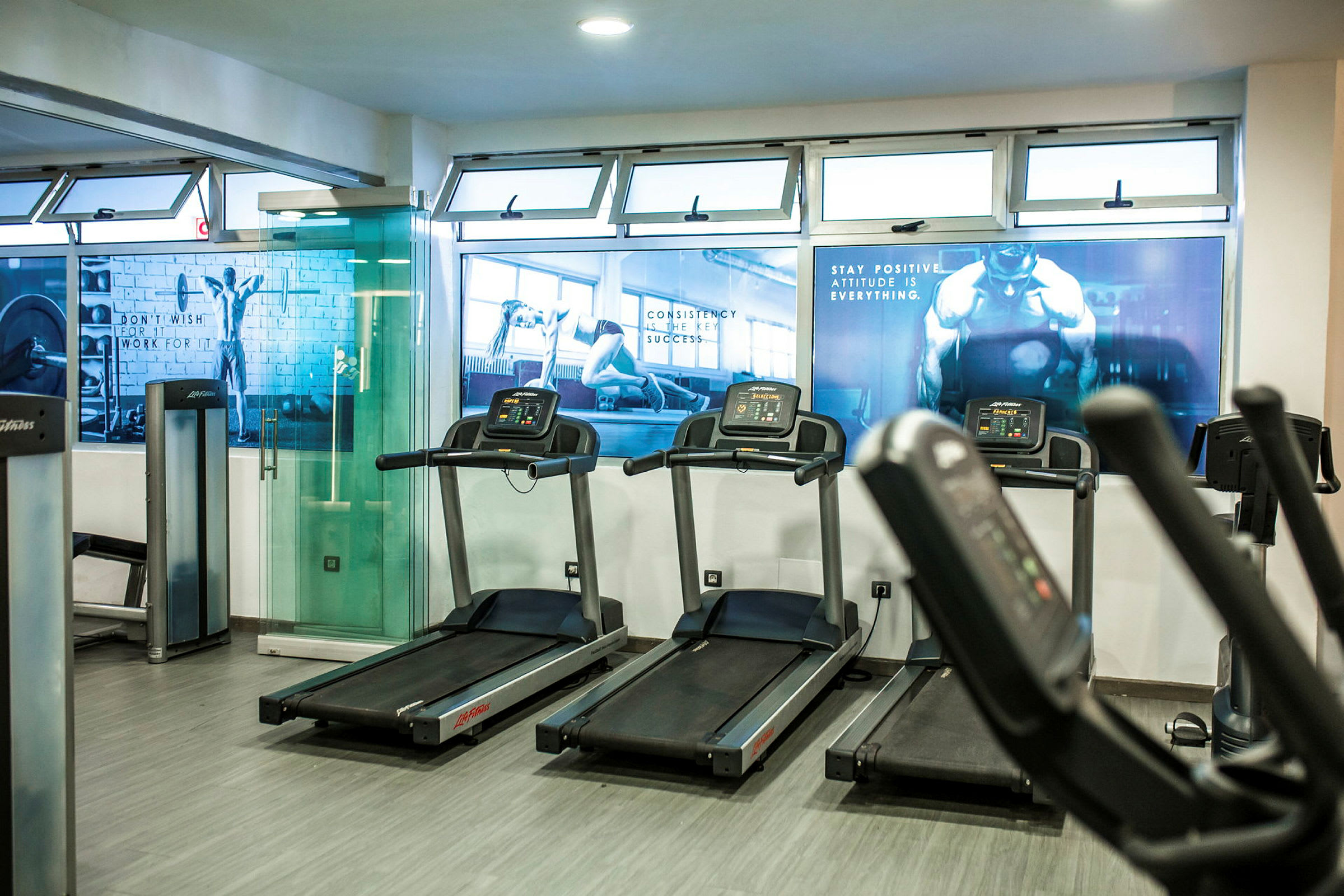 Ett gym med löpband och träningsmaskiner. Motivationsbilder är uppsatta på väggarna. (AI-genererad text)