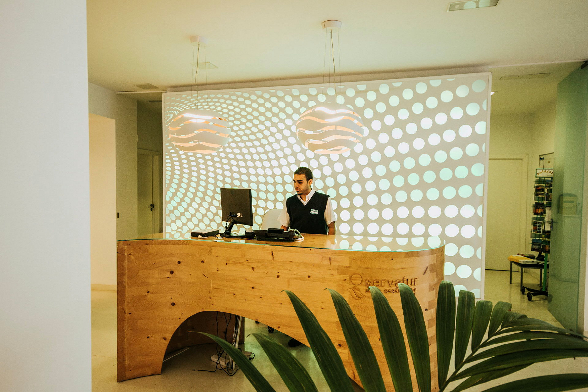Reception med trädisk och dator mot en bakgrund med cirkulärt mönster. (AI-genererad text)