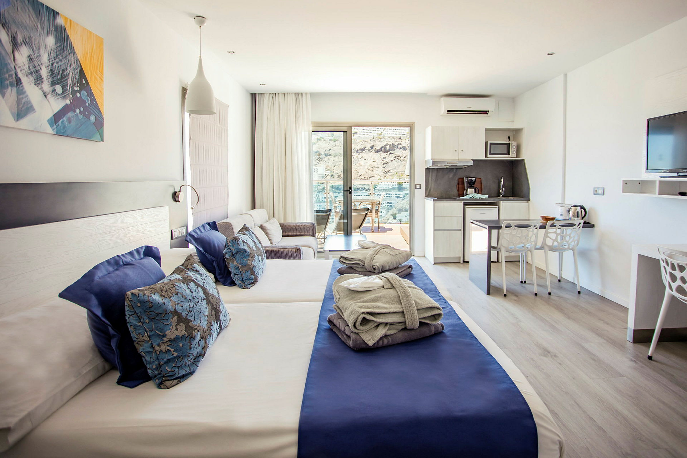 Ett hotellrum med två enkelsängar, sittgrupp, kök och uteplats. (AI-genererad text)