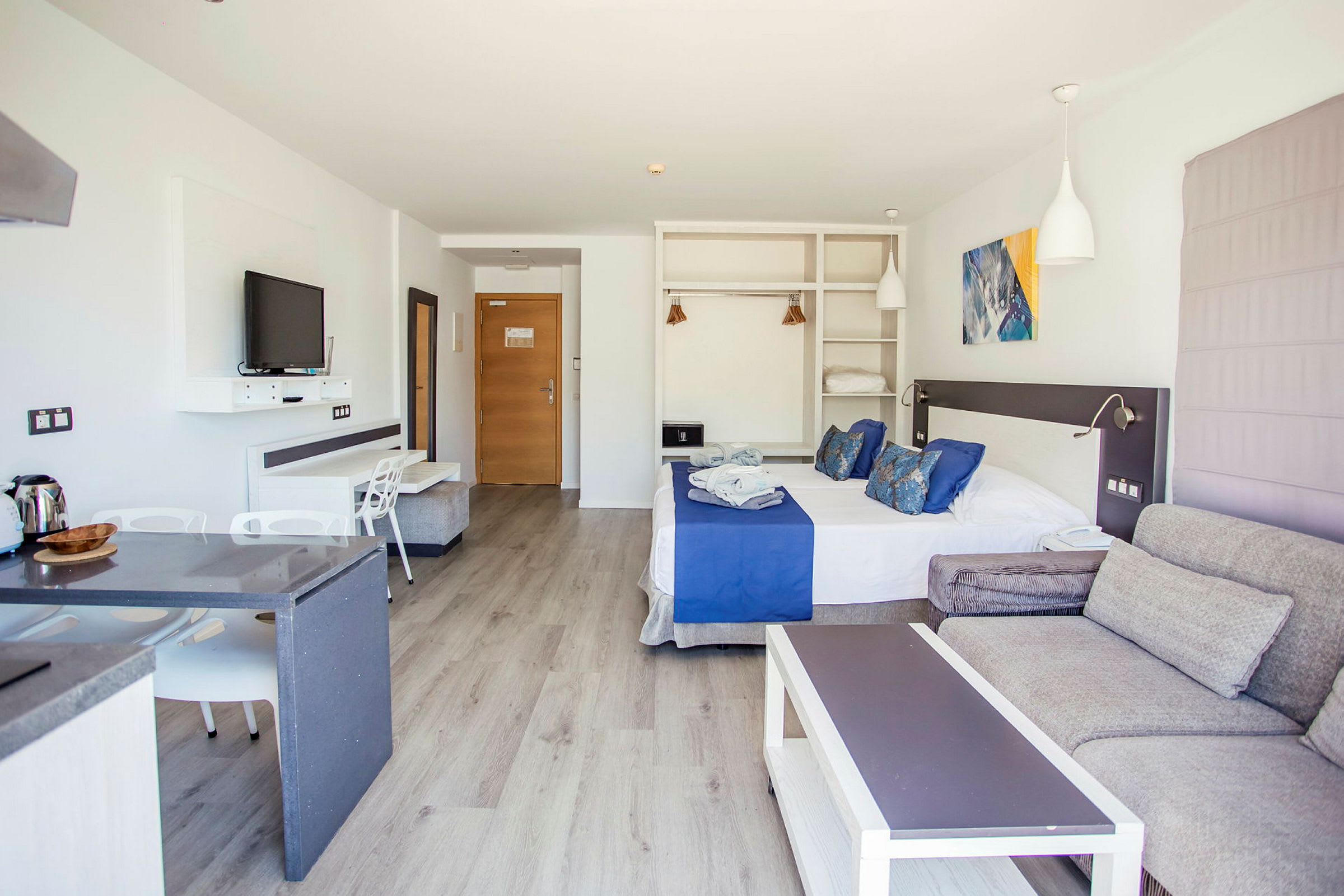 Ett hotellrum med dubbelbädd, sittgrupp och köksdel. (AI-genererad text)