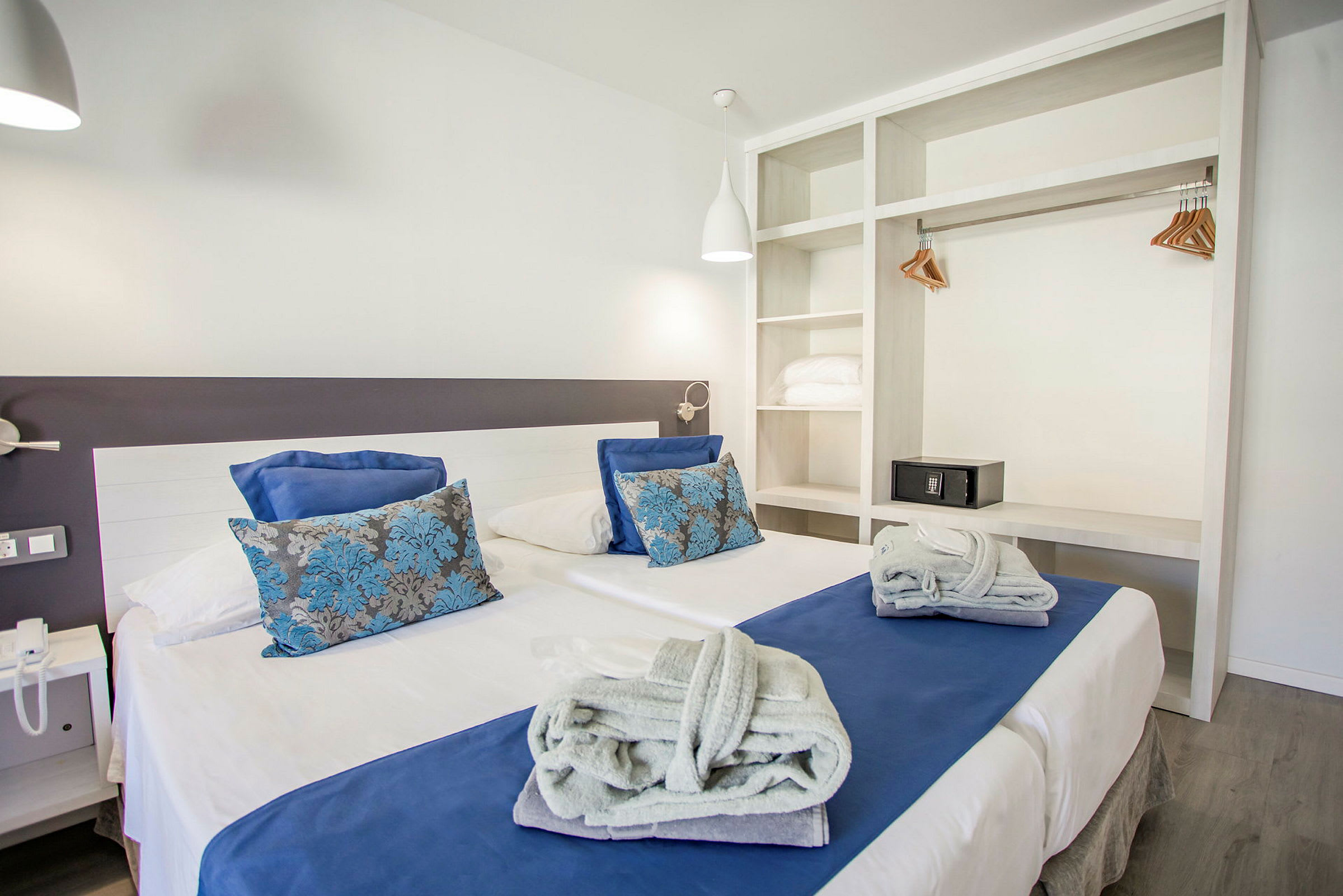 Bild av ett hotellrum med en modern design och en dubbelsäng klädd med vita och blå sängkläder. (AI-genererad text)