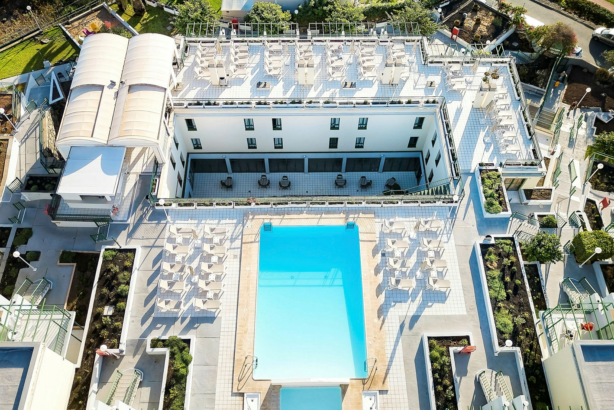Fågelvy av hotellområde med pool och solstolar. (AI-genererad text)