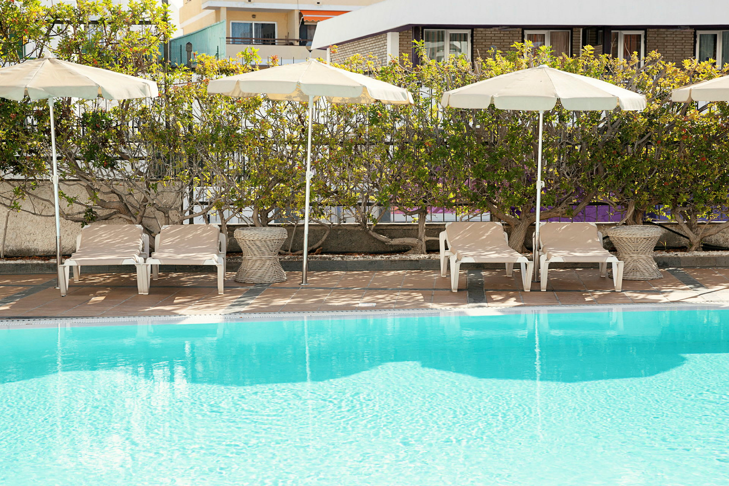 Solstolar med parasoller vid sidan av en pool. (AI-genererad text)