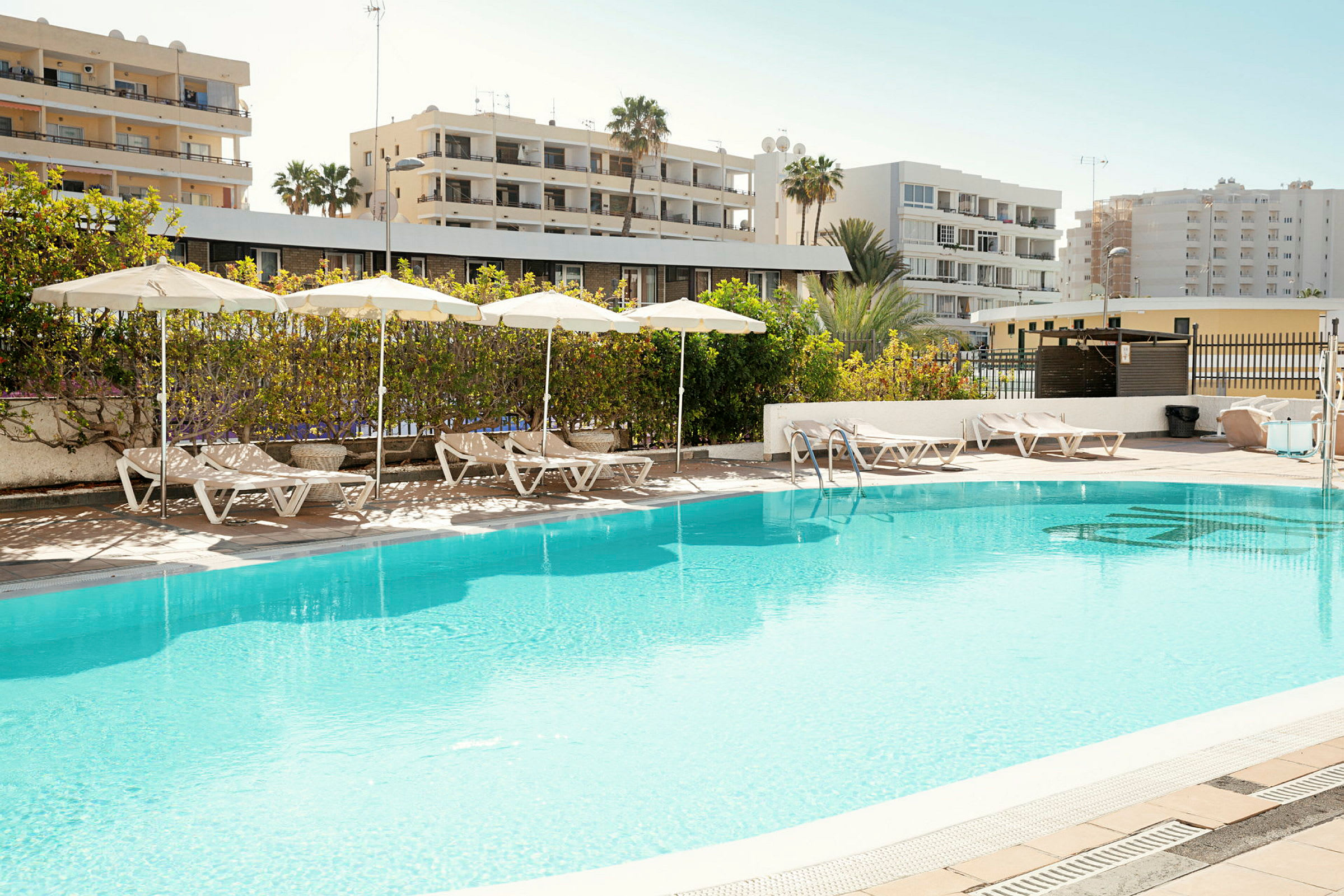 Utomhuspool med solstolar och parasoller på poolområdet. (AI-genererad text)