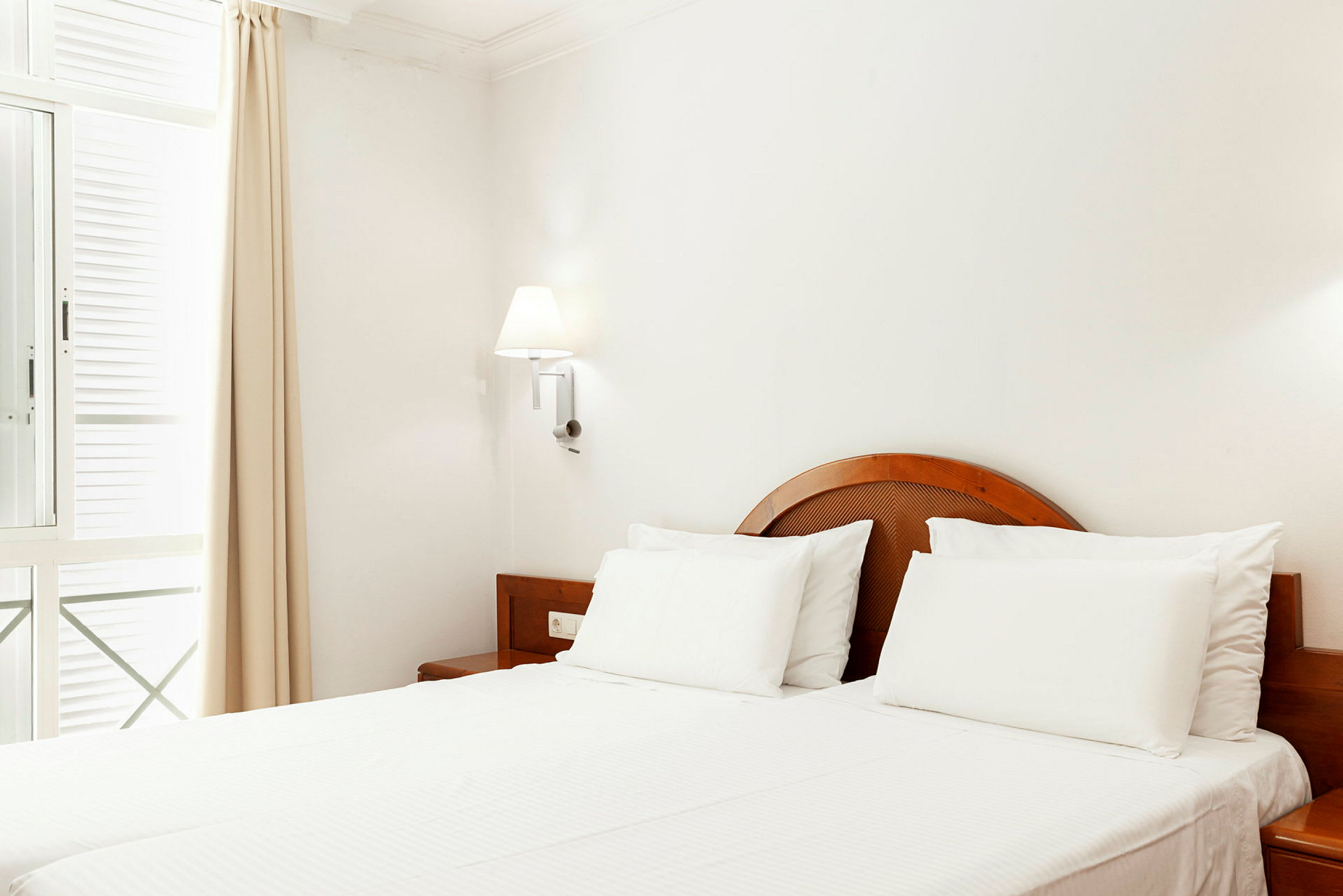 Ljust hotellrum med en dubbelsäng och träinredning. (AI-genererad text)