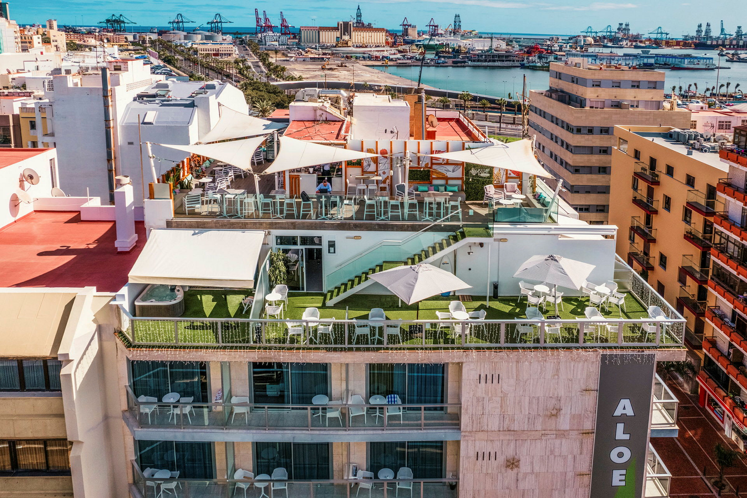 Hotellterrass med sittgrupper, parasoller och utsikt över staden och hamnen. (AI-genererad text)