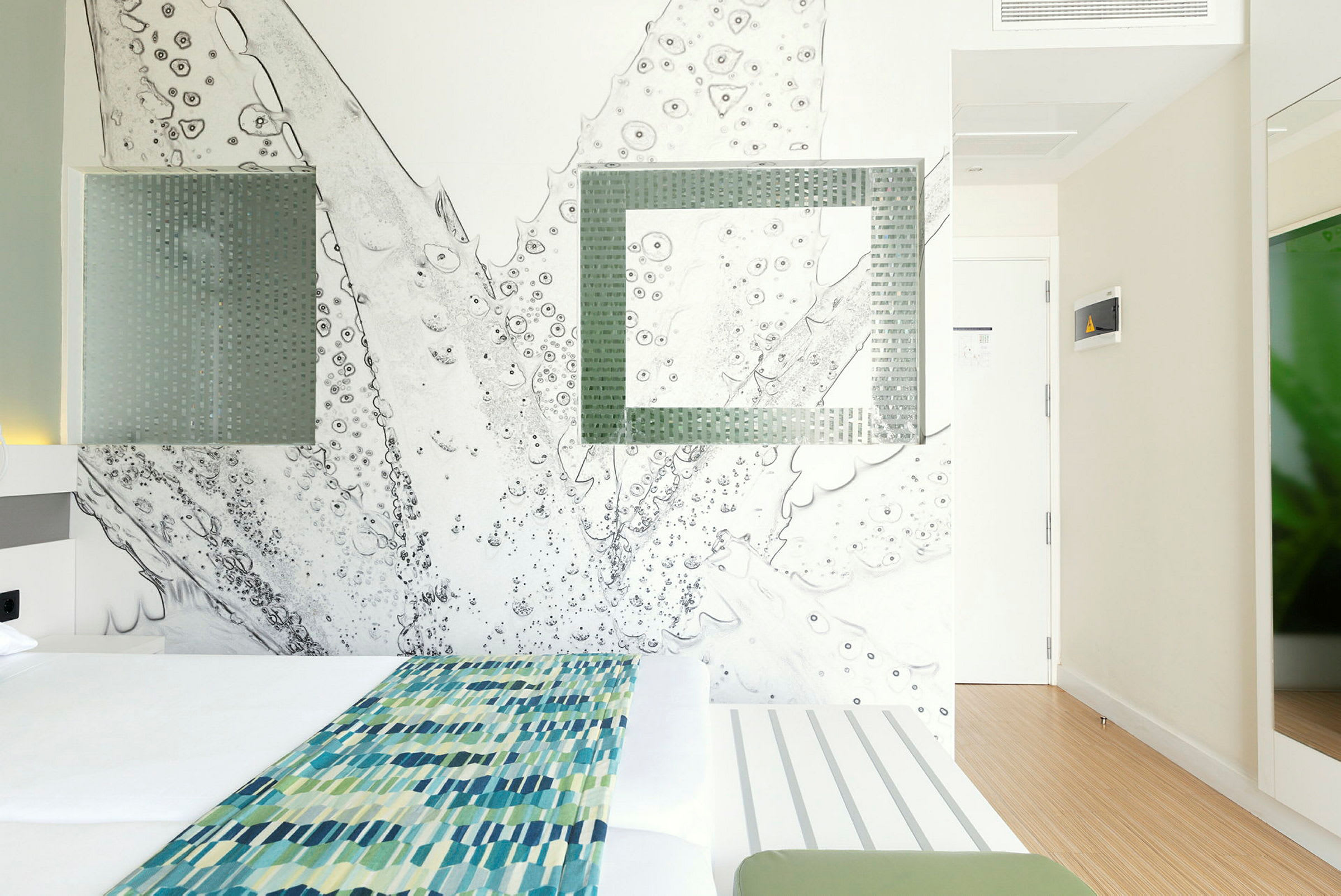 Modernt designat hotellrum med en dubbelsäng och abstrakt väggkonst. (AI-genererad text)
