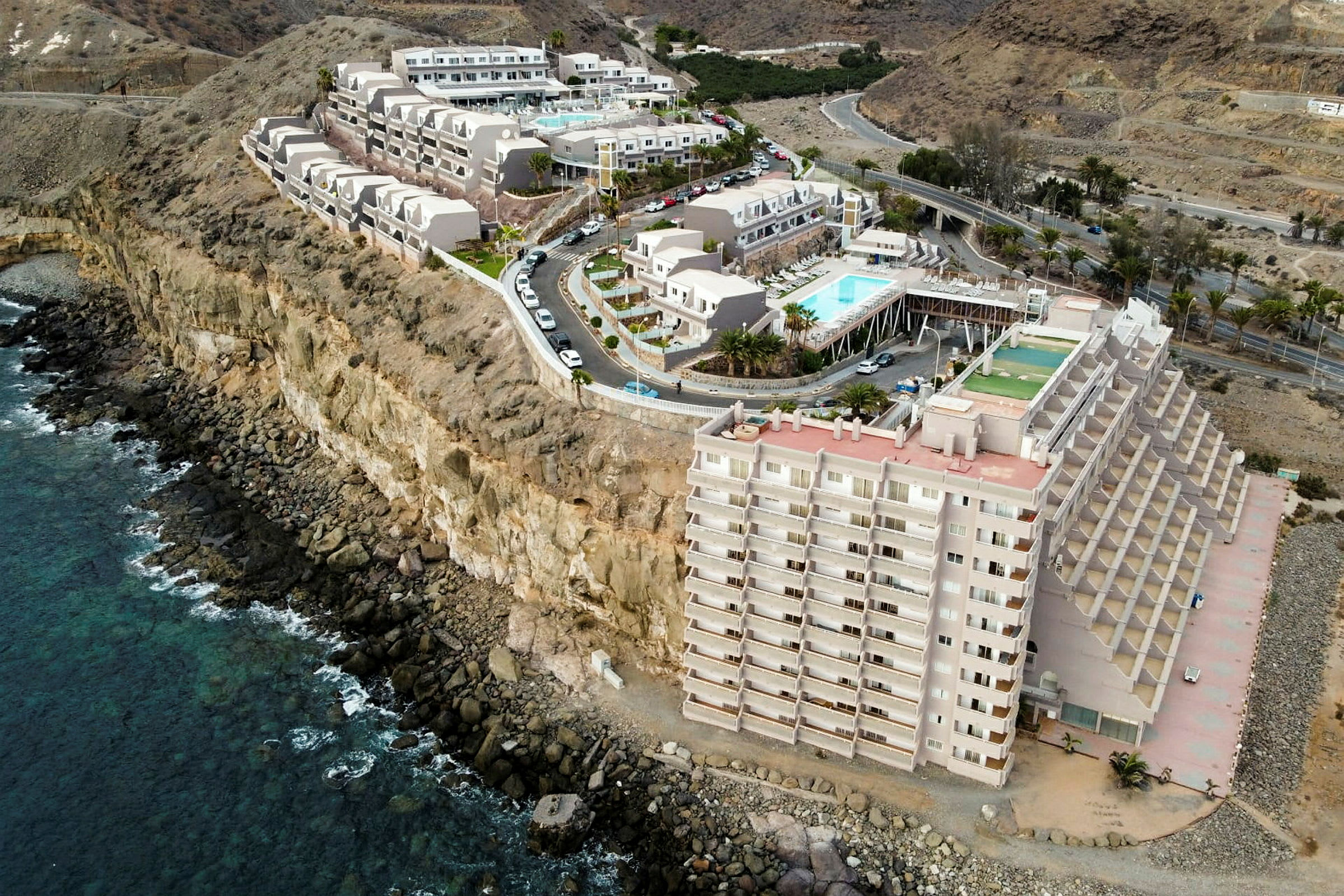 Hotellbyggnad vid en klippkust med havet i förgrunden. (AI-genererad text)