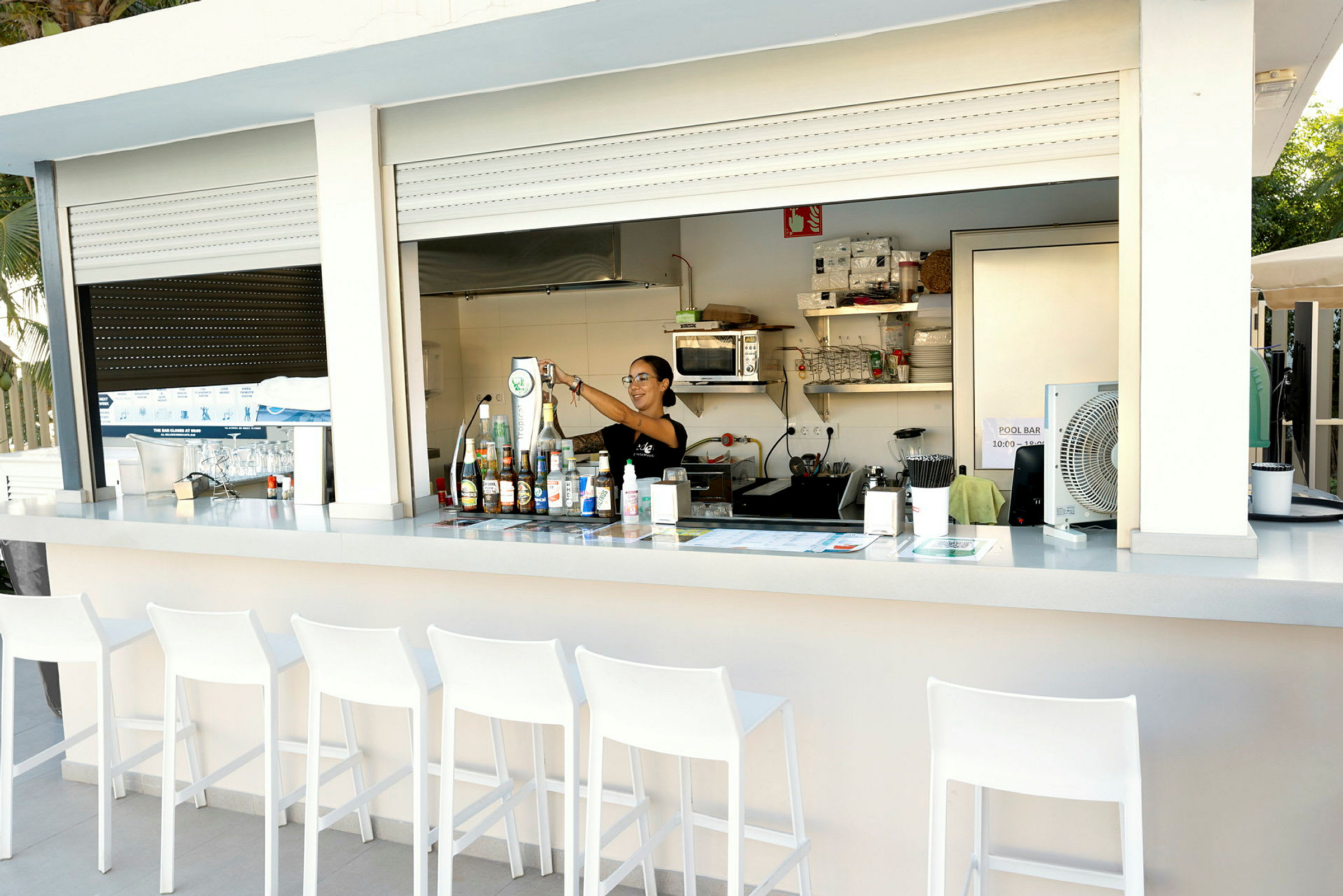 En poolbar med stolar framför. Flaskor och utrustning syns på bardisken. (AI-genererad text)