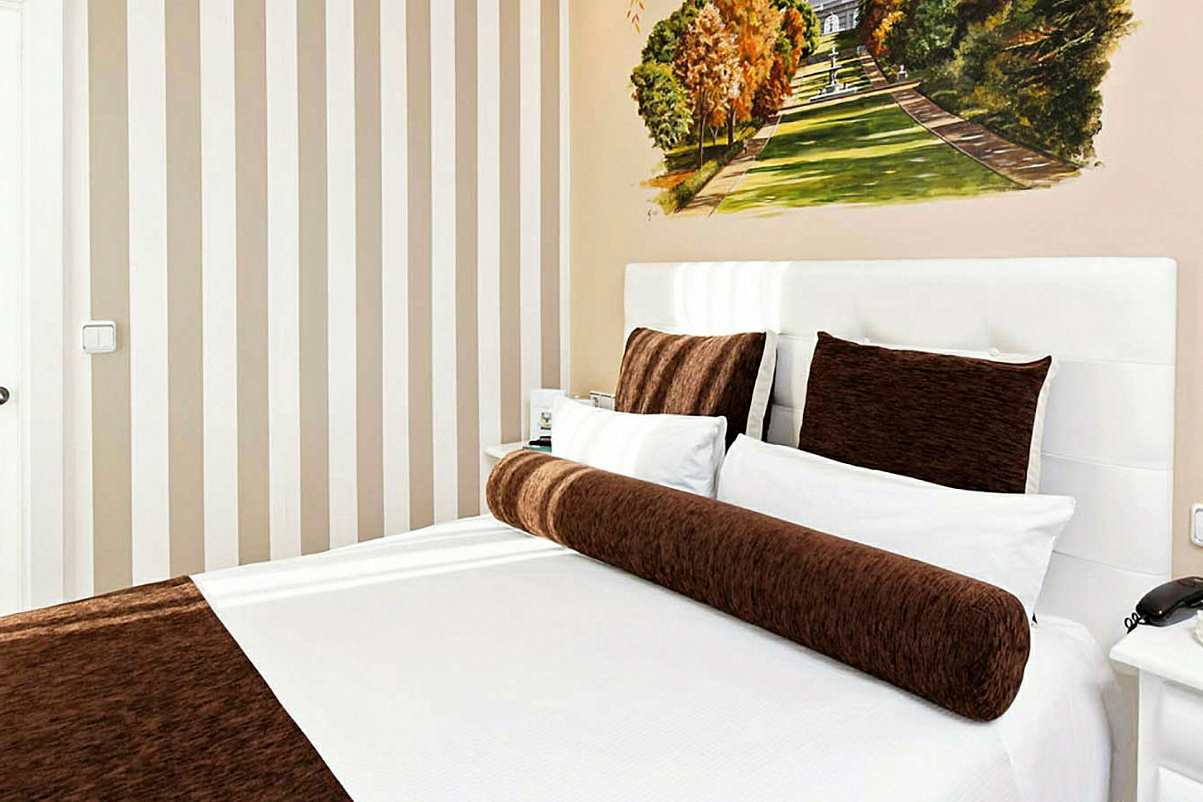 Ett hotellrum med en säng bäddad med vita och bruna sängkläder. (AI-genererad text)