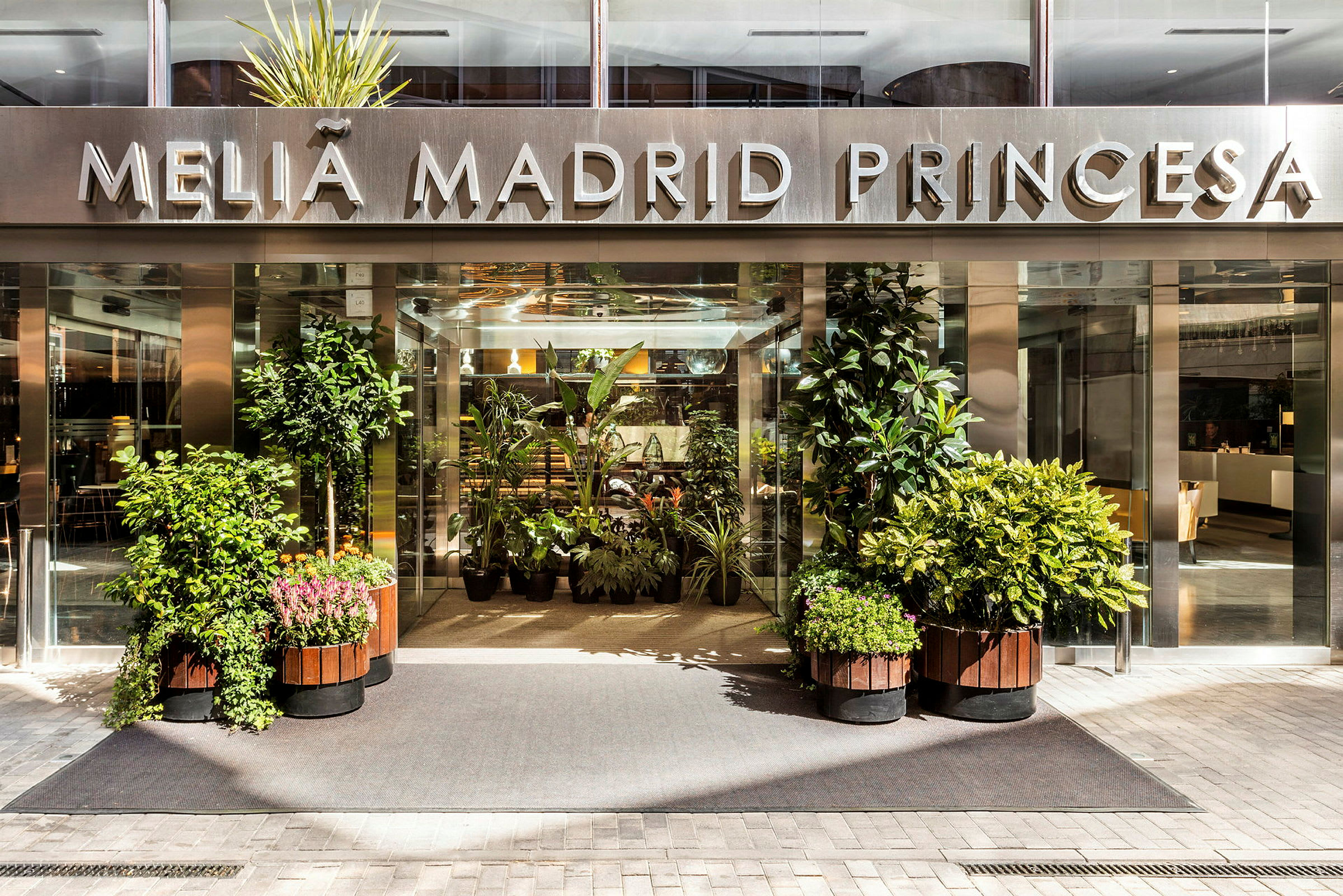 Hotellentré med skylt "Meliá Madrid Princesa" och omgivande växter. (AI-genererad text)