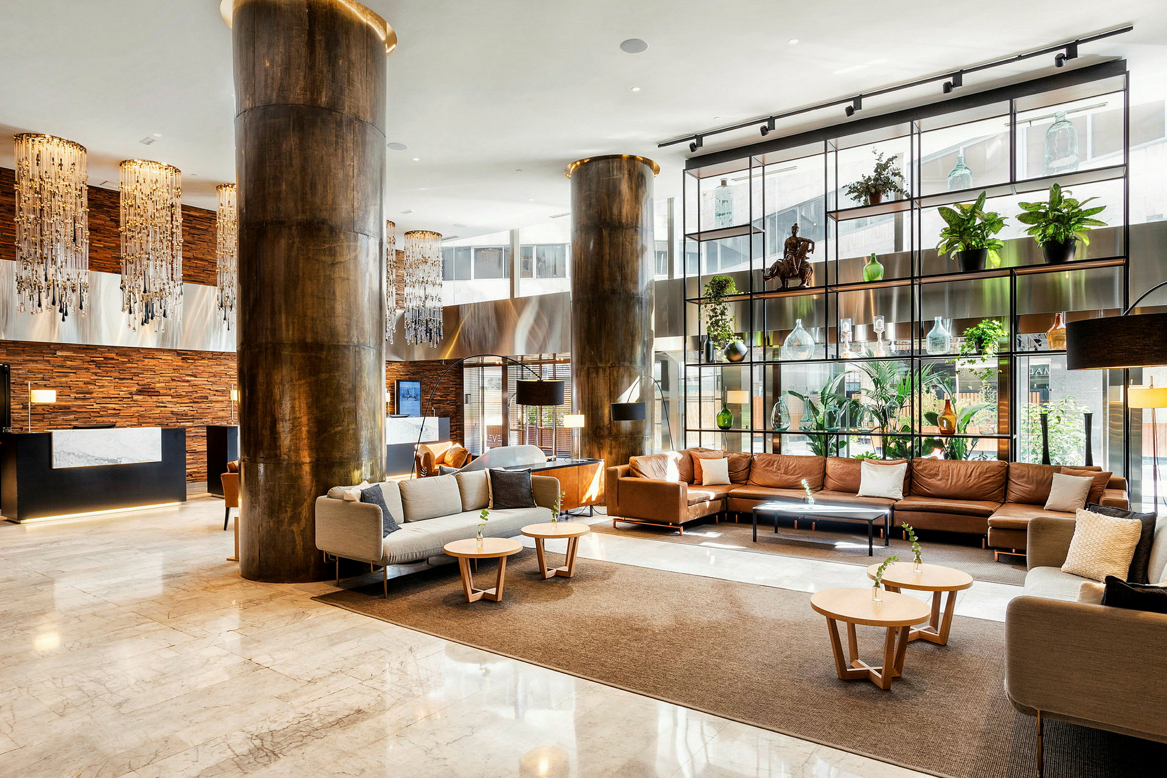 Ett modernt hotelllobby med lyxig inredning inklusive soffor och fåtöljer, dekorationer, växter och belysning. (AI-genererad text)