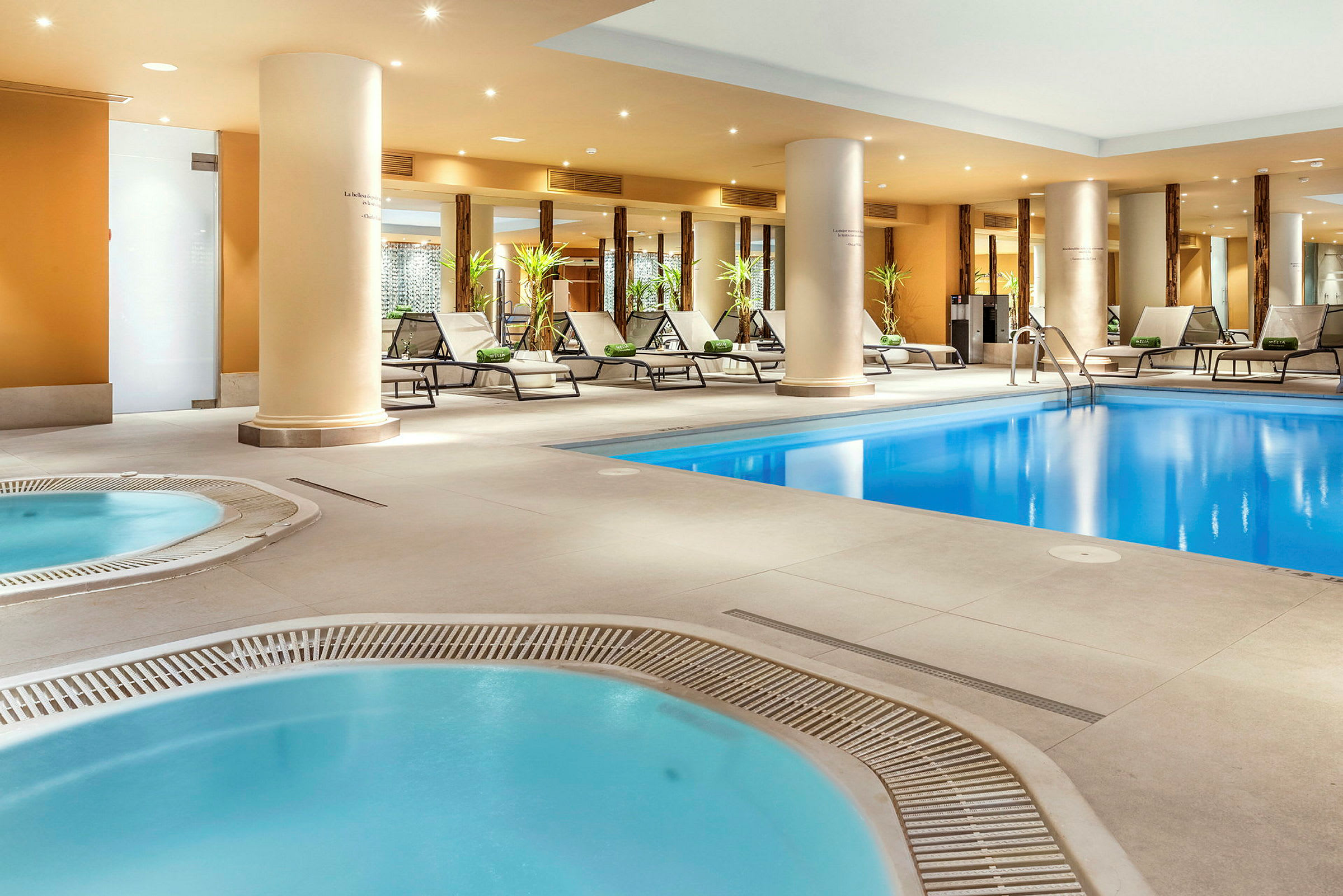 En inomhuspool och flera jacuzziområden omgivna av solstolar. (AI-genererad text)