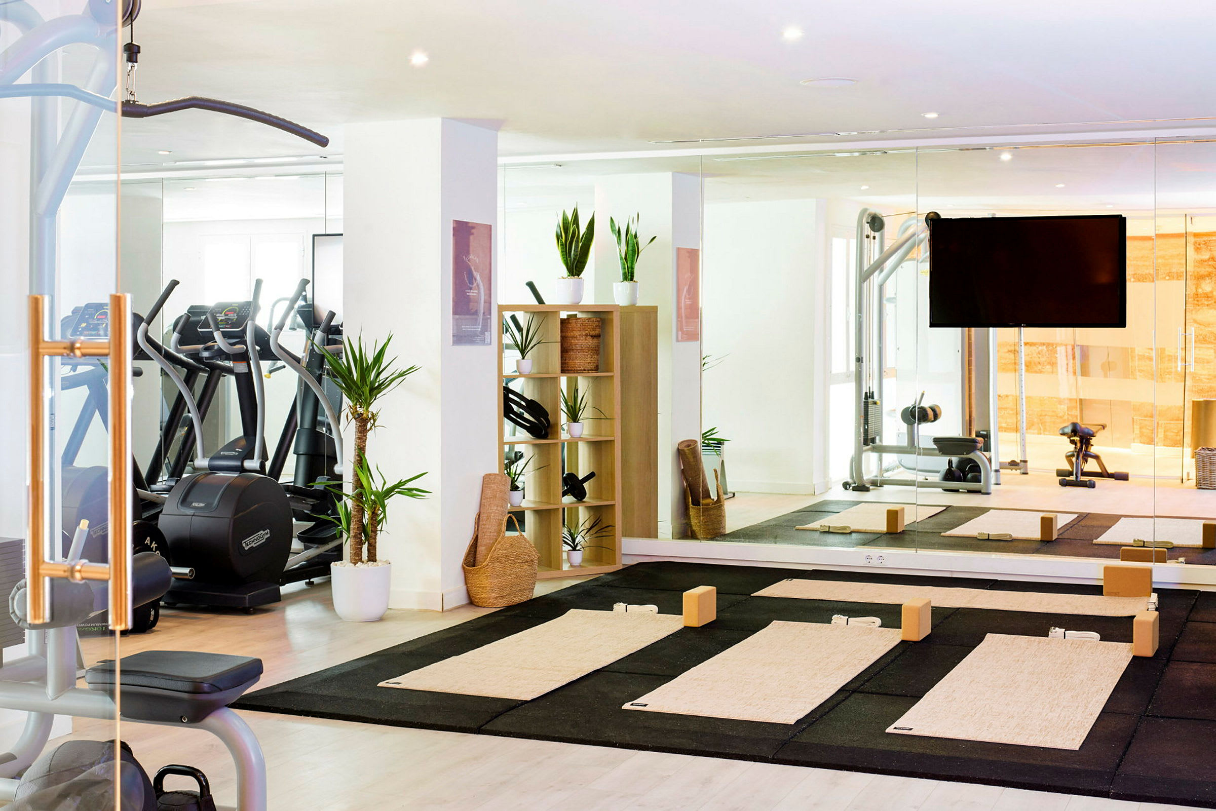 Ett gymrum med yogamattor på golvet, spegelväggar och träningsutrustning. (AI-genererad text)